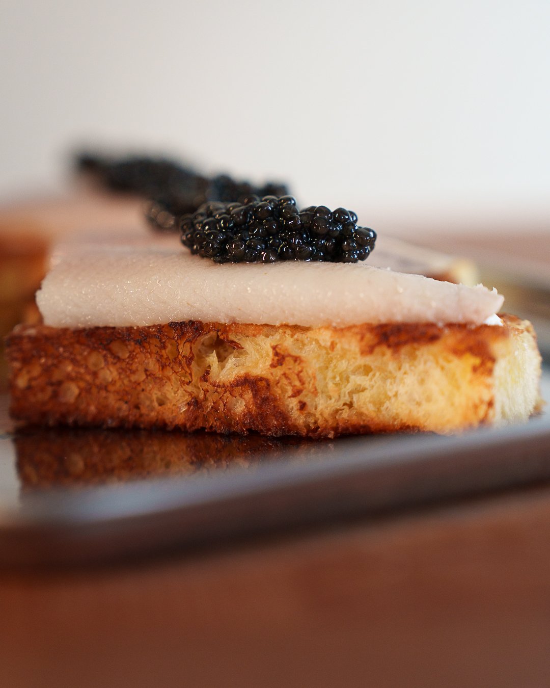 Close-up of toasted bread topped with a white creamy substance and black caviar.