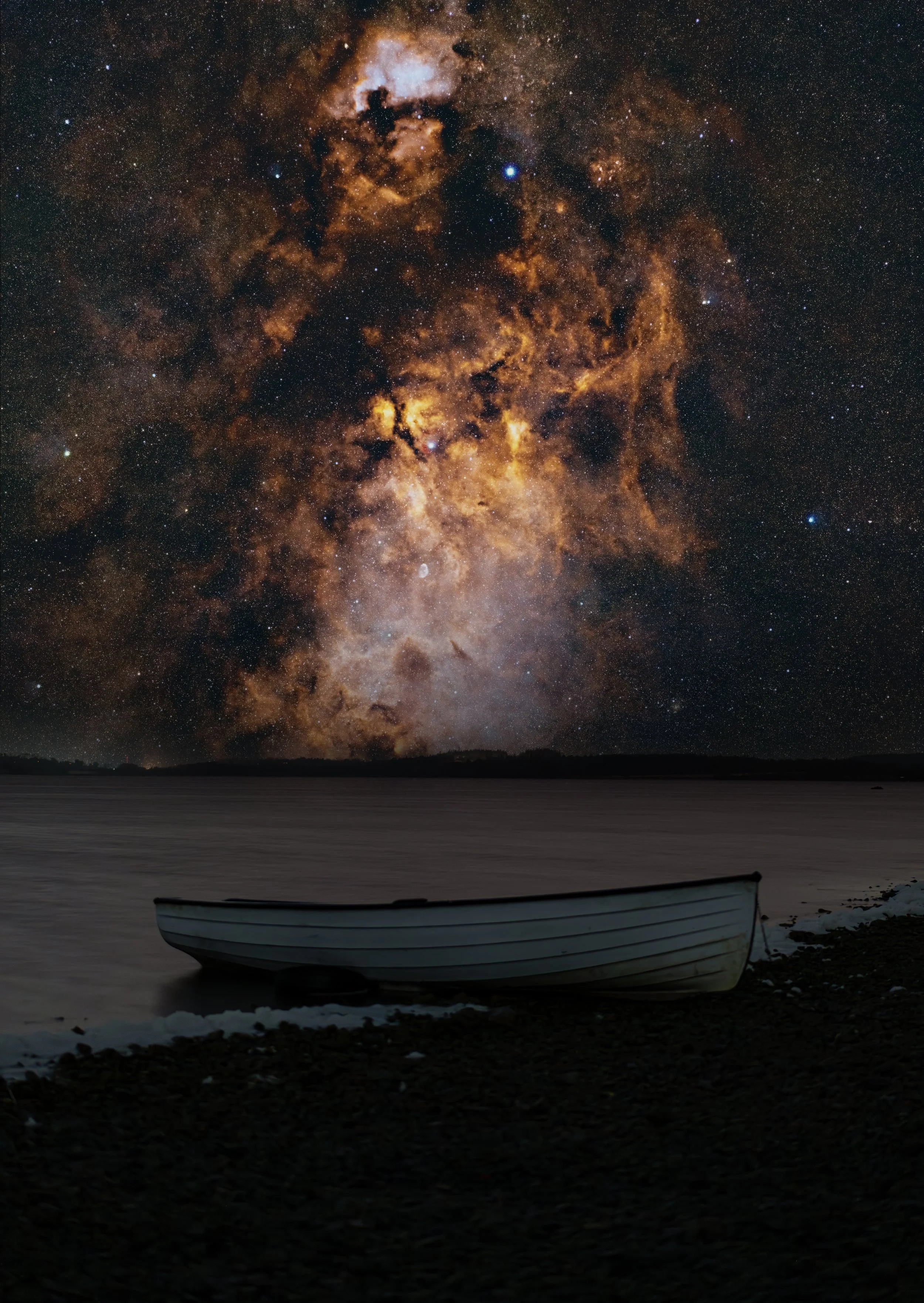 A boat resting on a rocky shoreline at nighttime with the Milky Way galaxy visible in the sky.