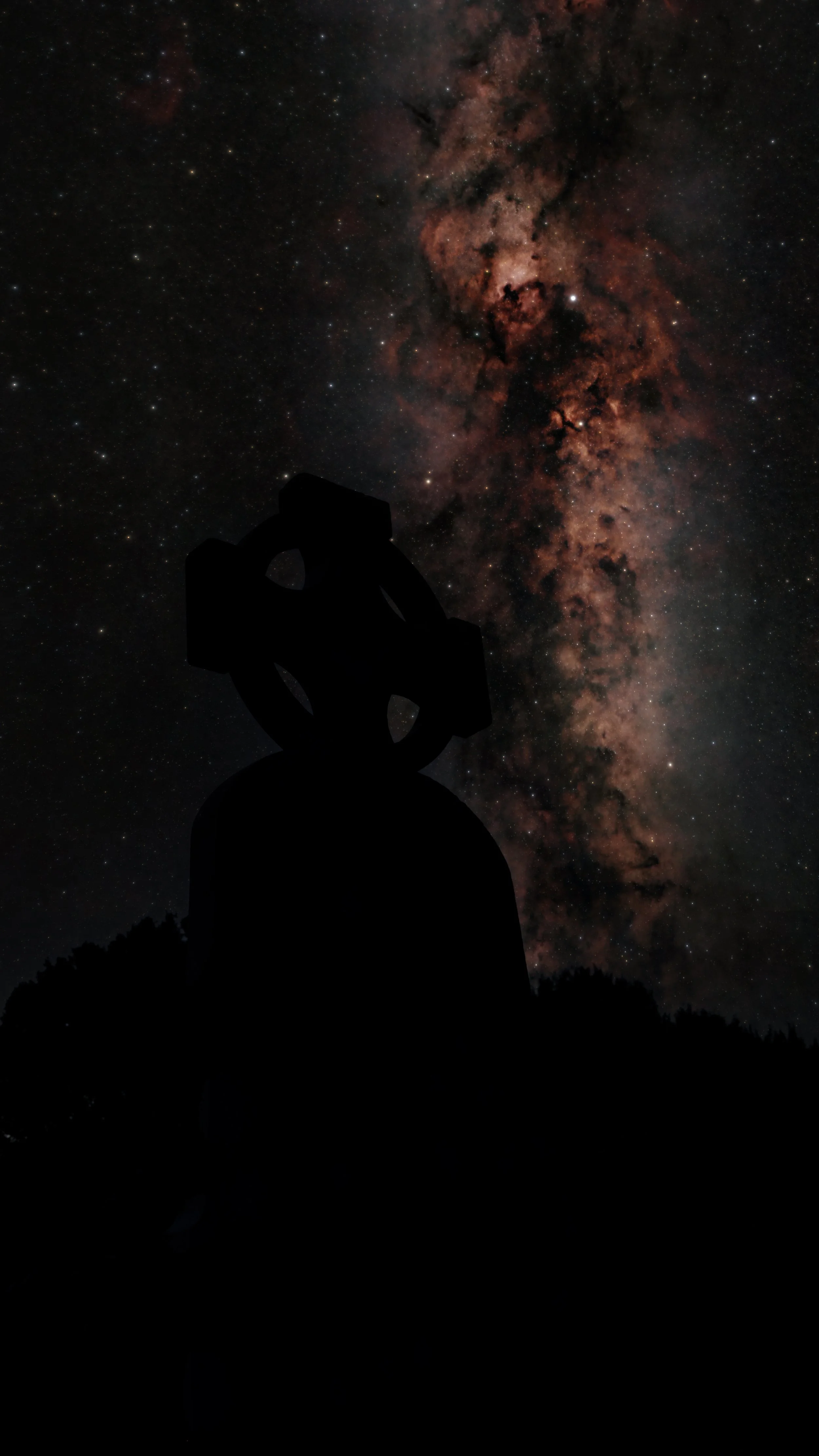 Silhouette of a Celtic cross in Glendalough against a starry night sky with a view of the Northern Cross and Cygnus nebula complex.