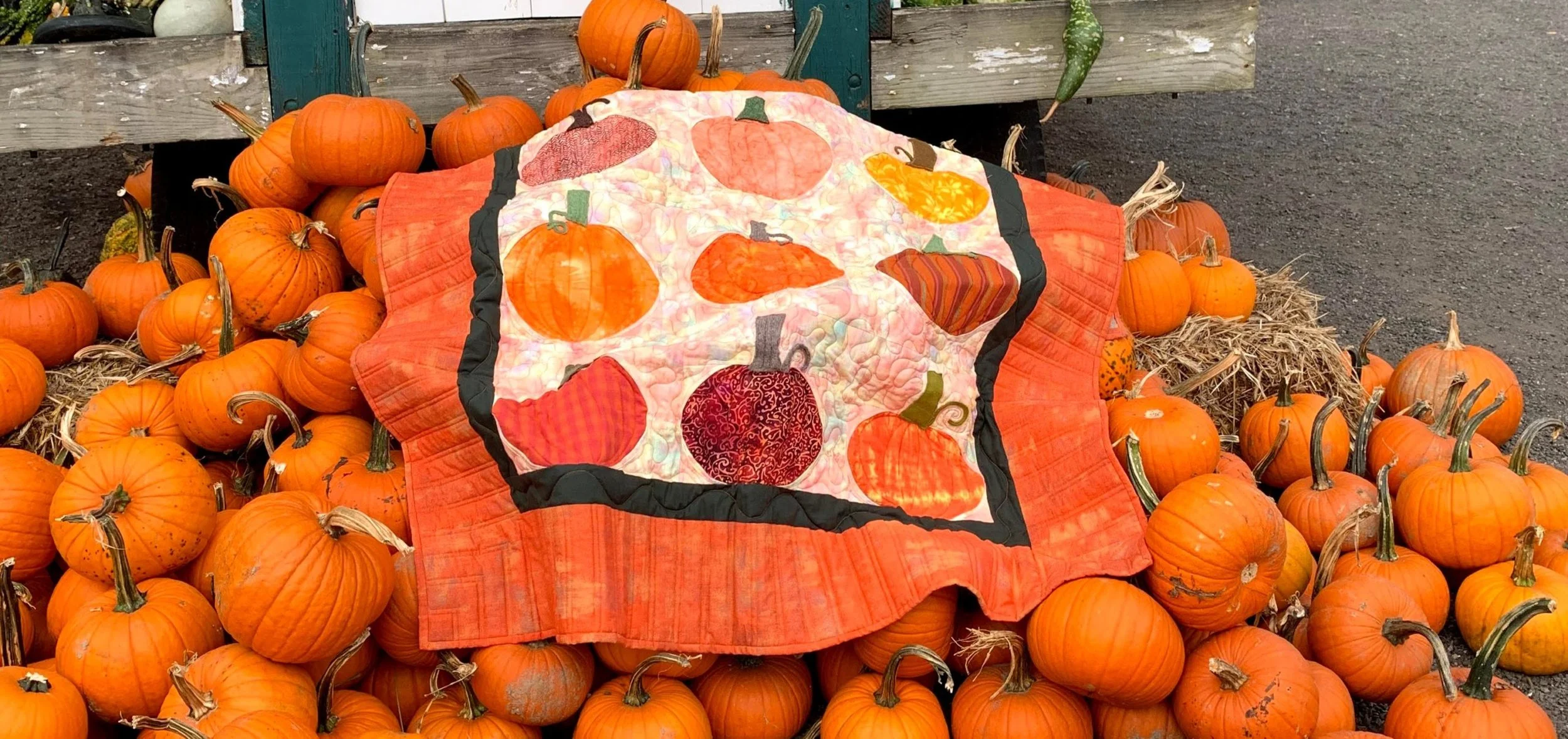 Pumpkin play quilt by dizzy quilter on a pile of pumpkins