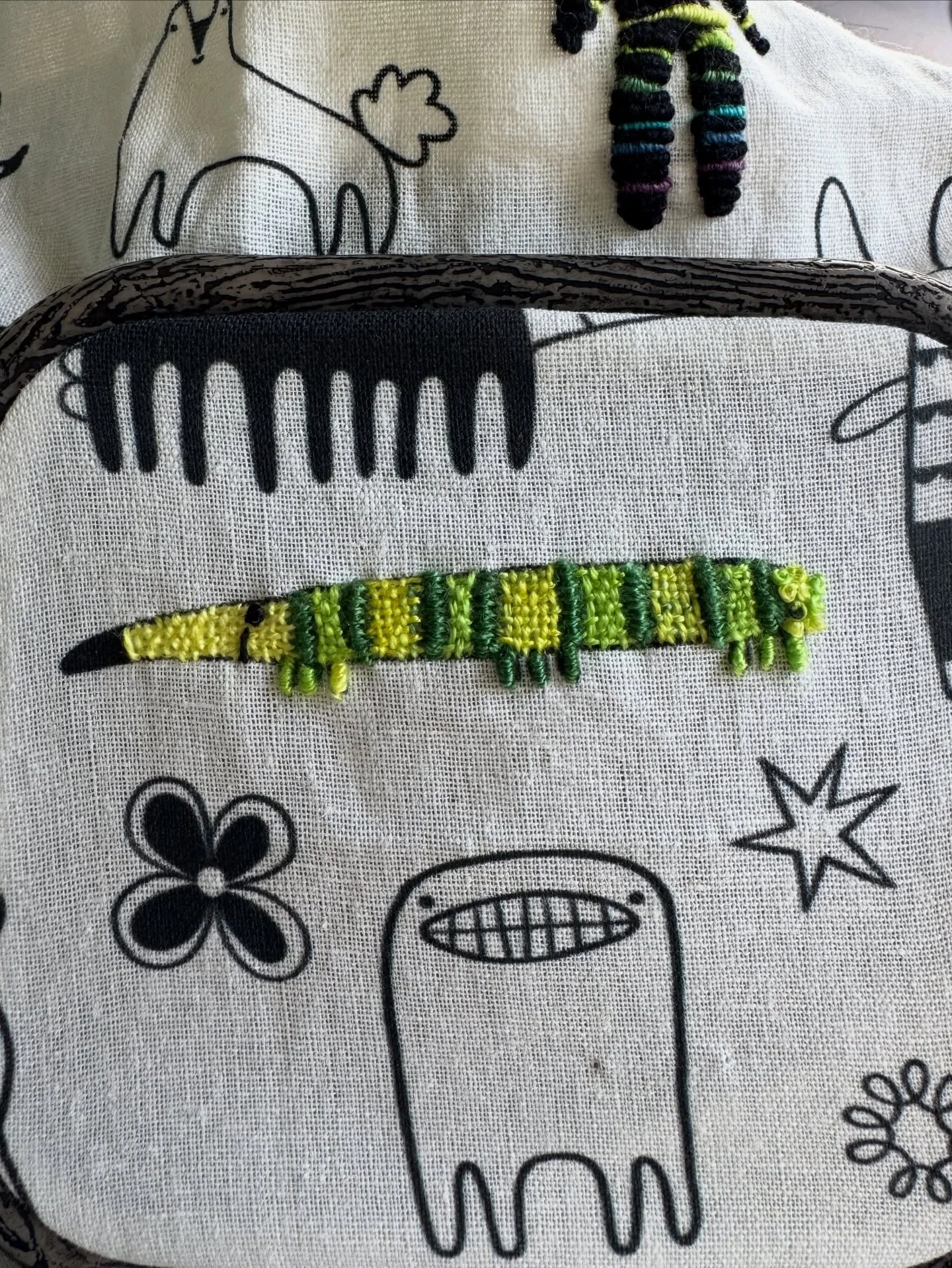 Another happy little weirdo. Stitches are double cast-on stitch in the dark green, which I anchored woven bits into. Bullion knot legs and a French knot for an eye, and he looks finished to me. Oh, a bunch of French knots on his butt, too, as my guys