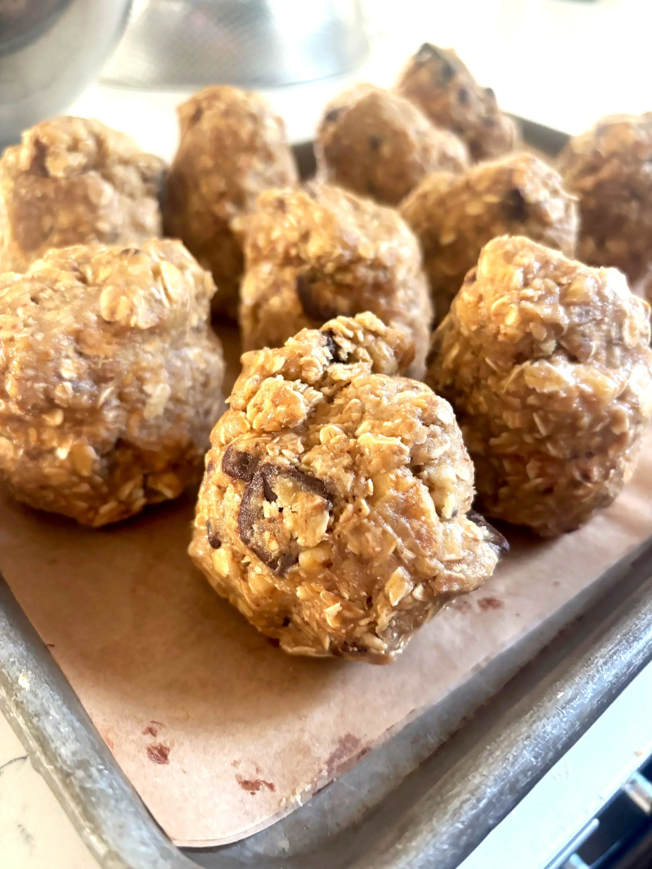 Close-up of homemade oatmeal chocolate chip cookies on baking sheet lined with parchment paper.