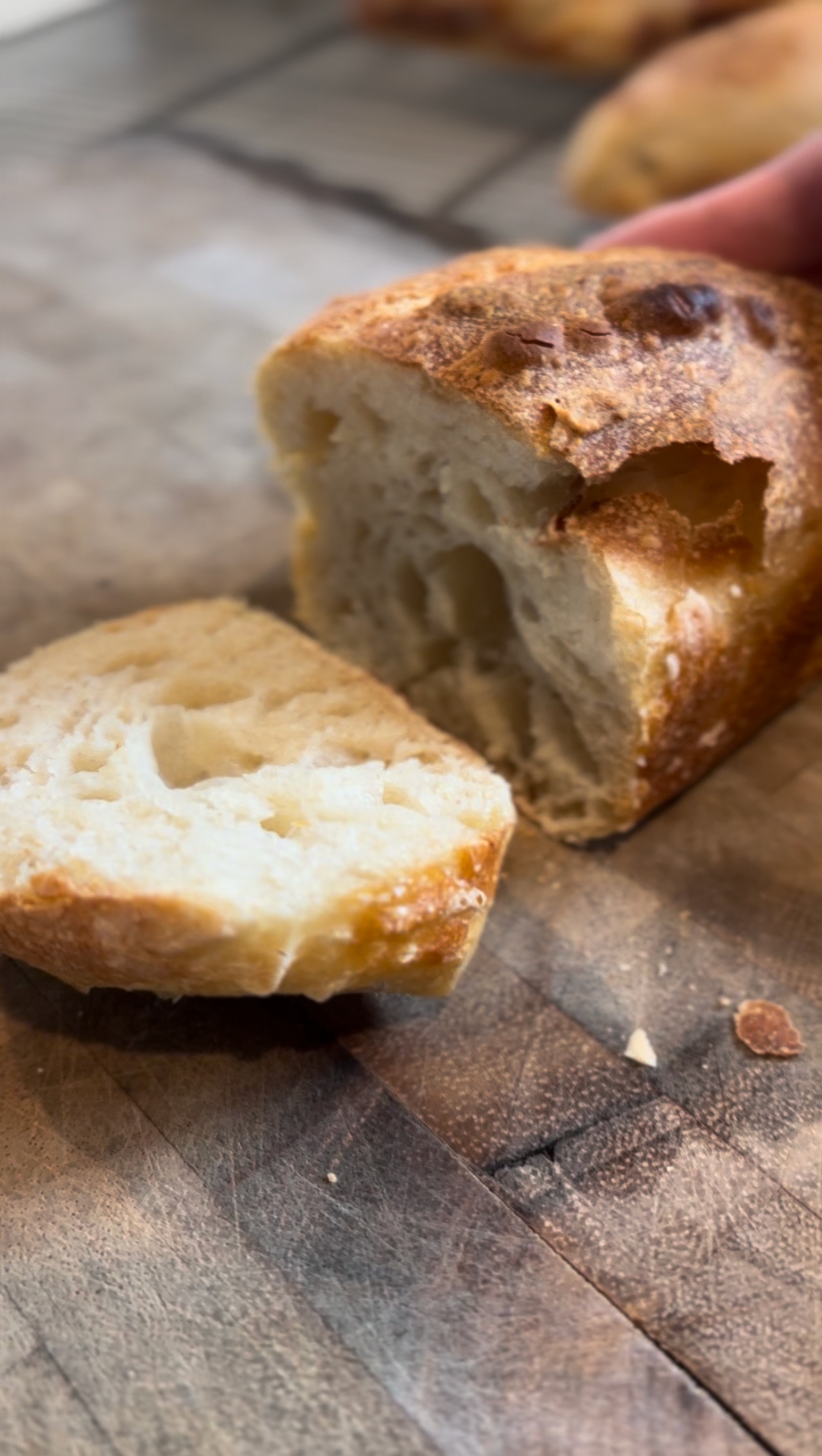 Close-up of a bread loaf torn open, showing its soft, airy interior on a wooden surface.