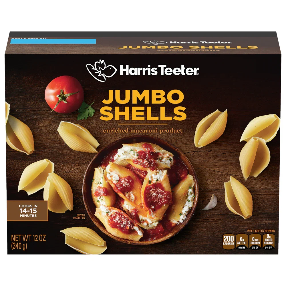 Packaging of Harris Teeter Jumbo Shells pasta with a bowl of cooked pasta and tomato sauce on top, surrounded by uncooked pasta shells and a tomato with green leaves.