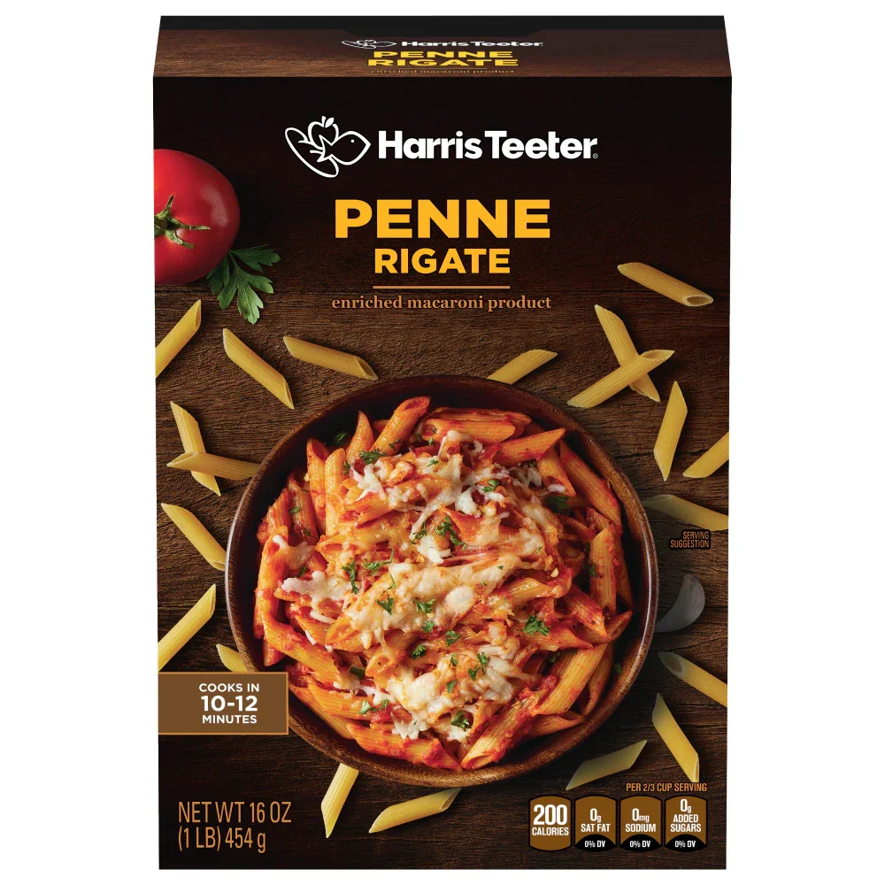 Box of Harris Teeter Penne Rigate enriched macaroni product with a bowl of prepared pasta, tomato, and cheese on the front, surrounded by scattered penne pasta, with a tomato and parsley garnish on the upper left.