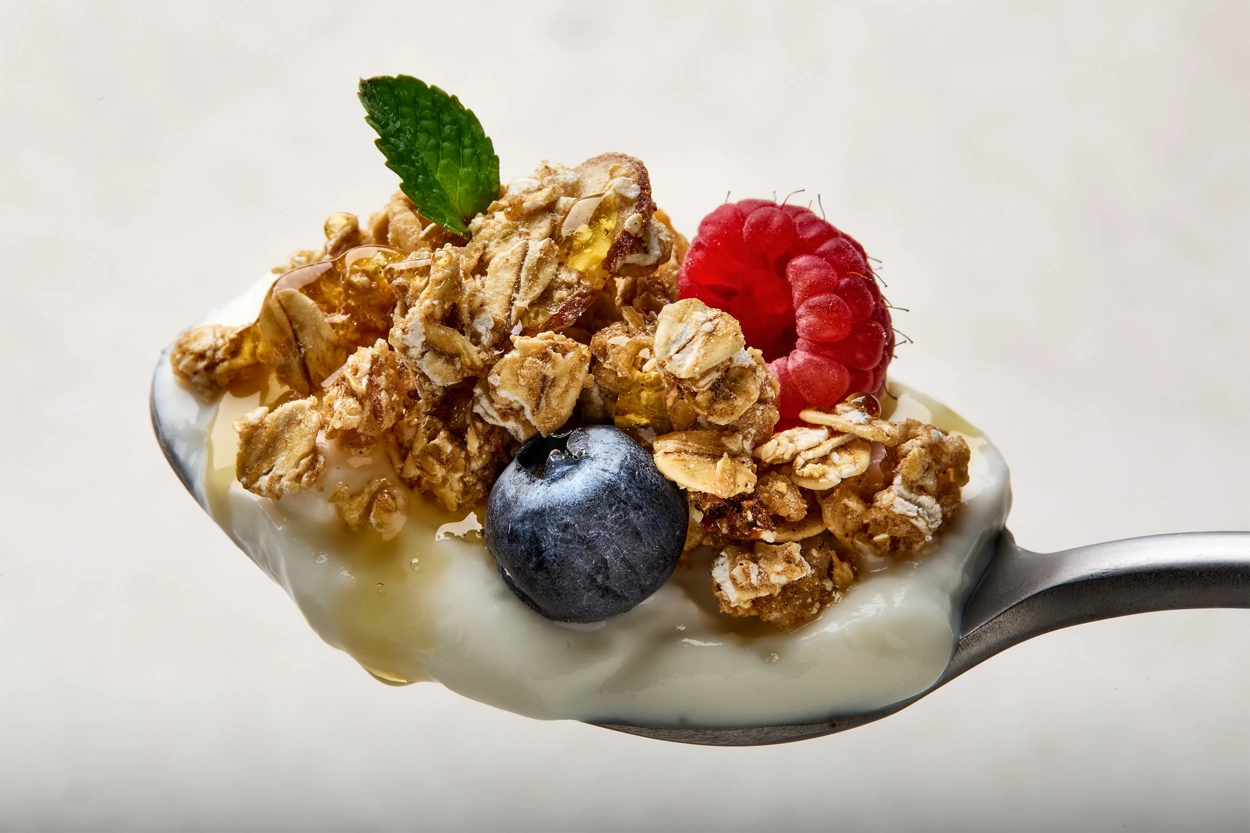 Yogurt with granola, blueberries, raspberry, and a mint leaf on top