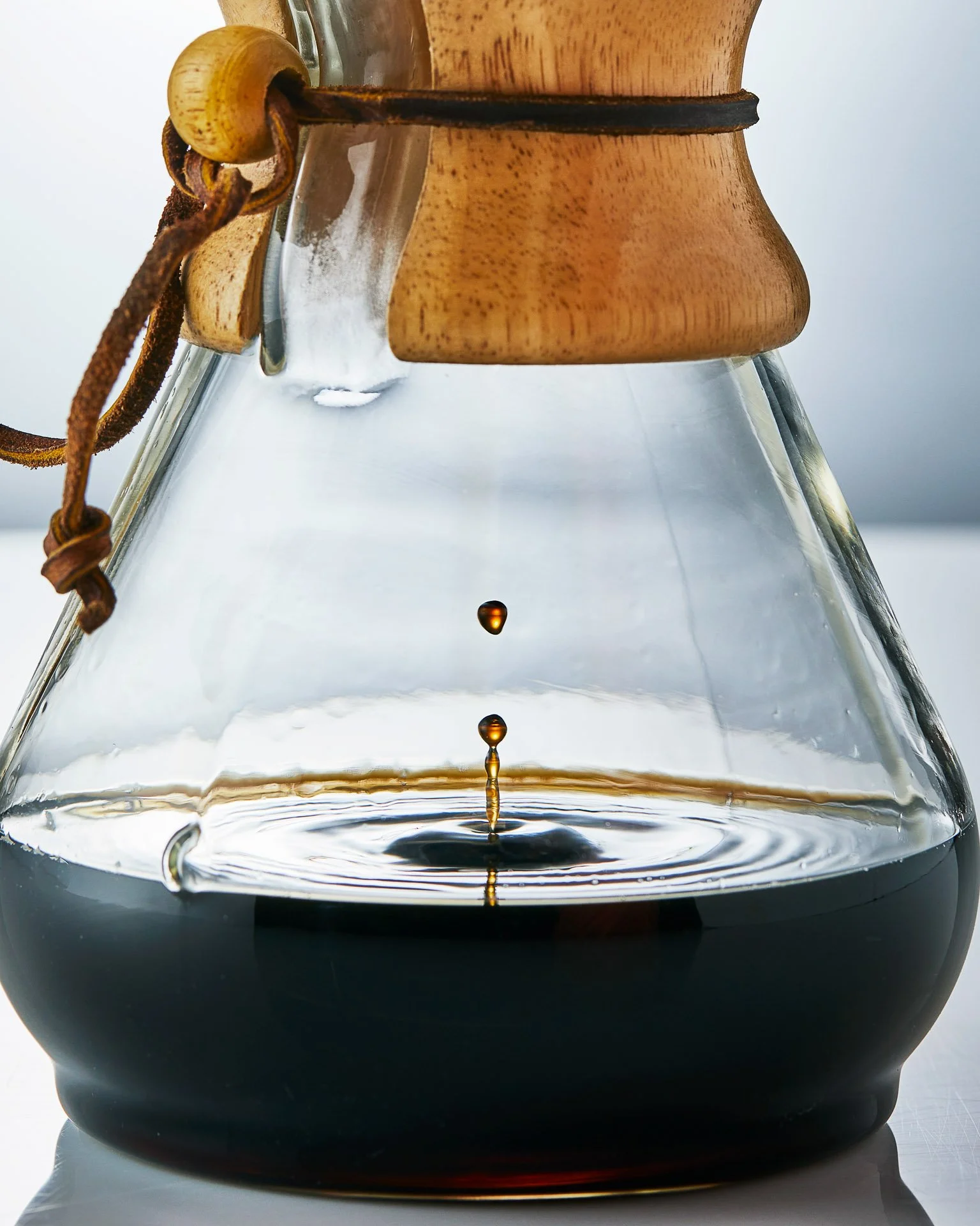 Close-up of a Chemex coffee maker with coffee dripping into it.