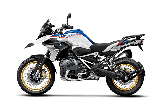 BMW adventure motorcycle with white, black, blue, and red colors, gold rims, and off-road tires.