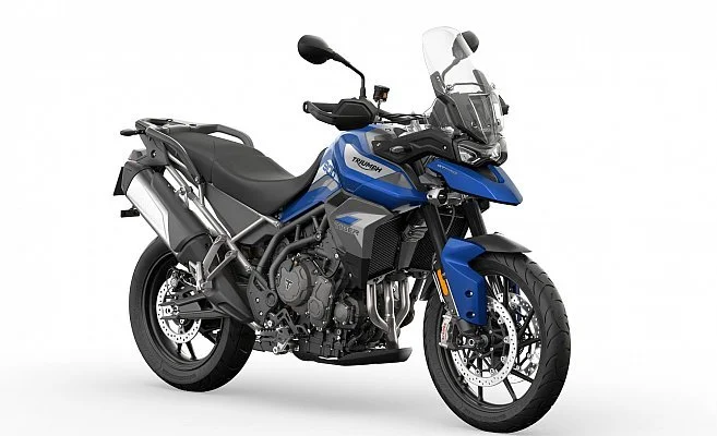 Blue and black Triumph adventure motorcycle with a windshield, front and rear suspension, and knobby tires, on a white background.