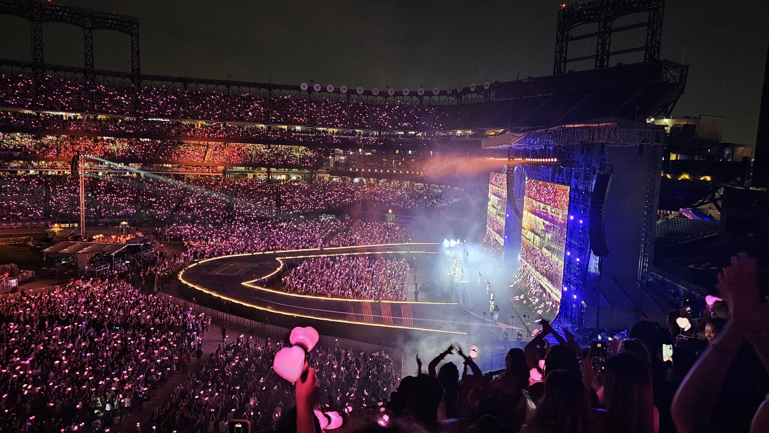 K-pop fans holding glowing lightsticks at a stadium concert, showing how Fanlayer UID-authenticated merchandise proves loyalty and identity beyond the show.