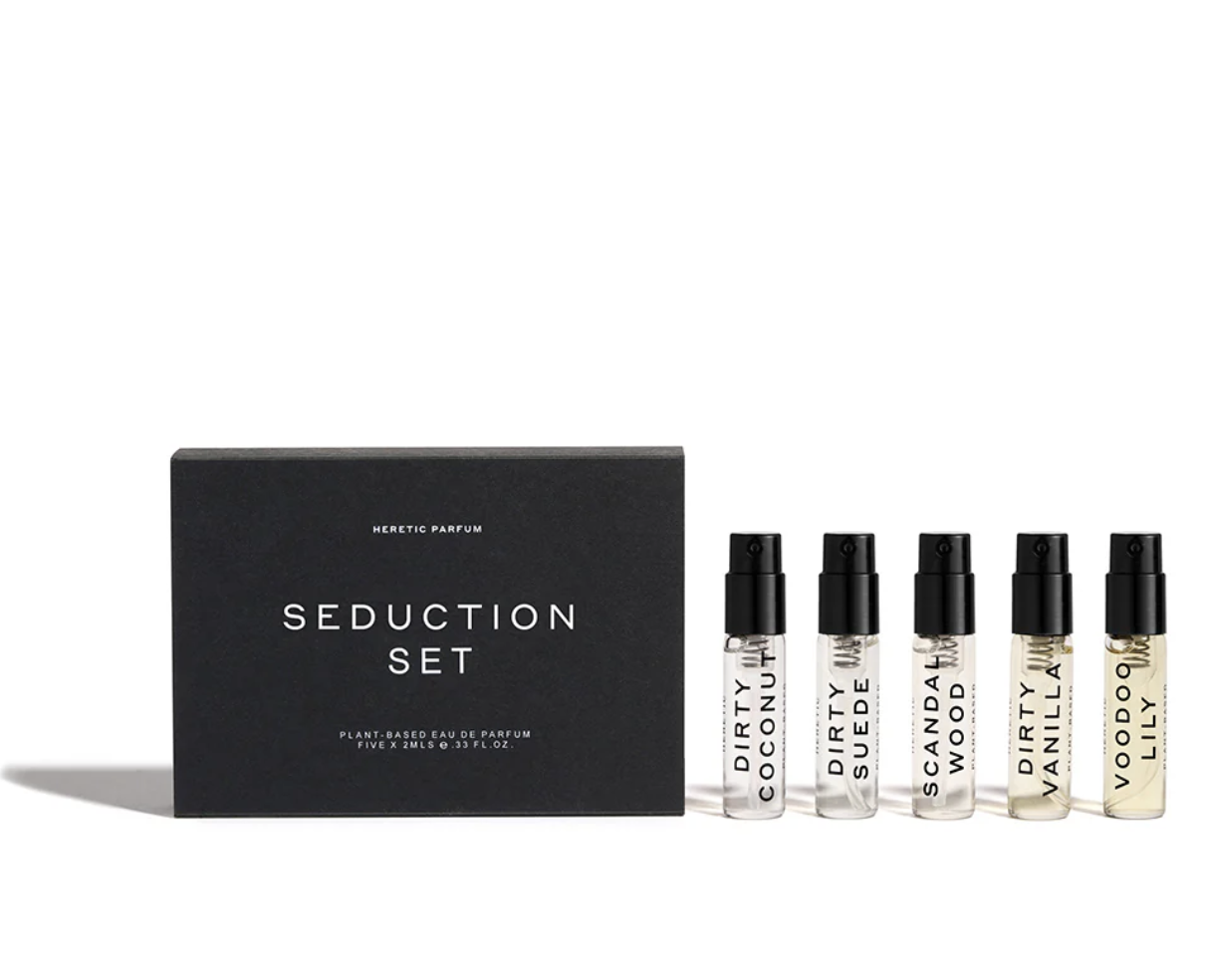 Set of five perfume vials labeled Dirty Coconut, Dirty Suede, Scandal Wood, Dirty Vanilla, and Voodoo Lilly beside a black box labeled Seduction Set.