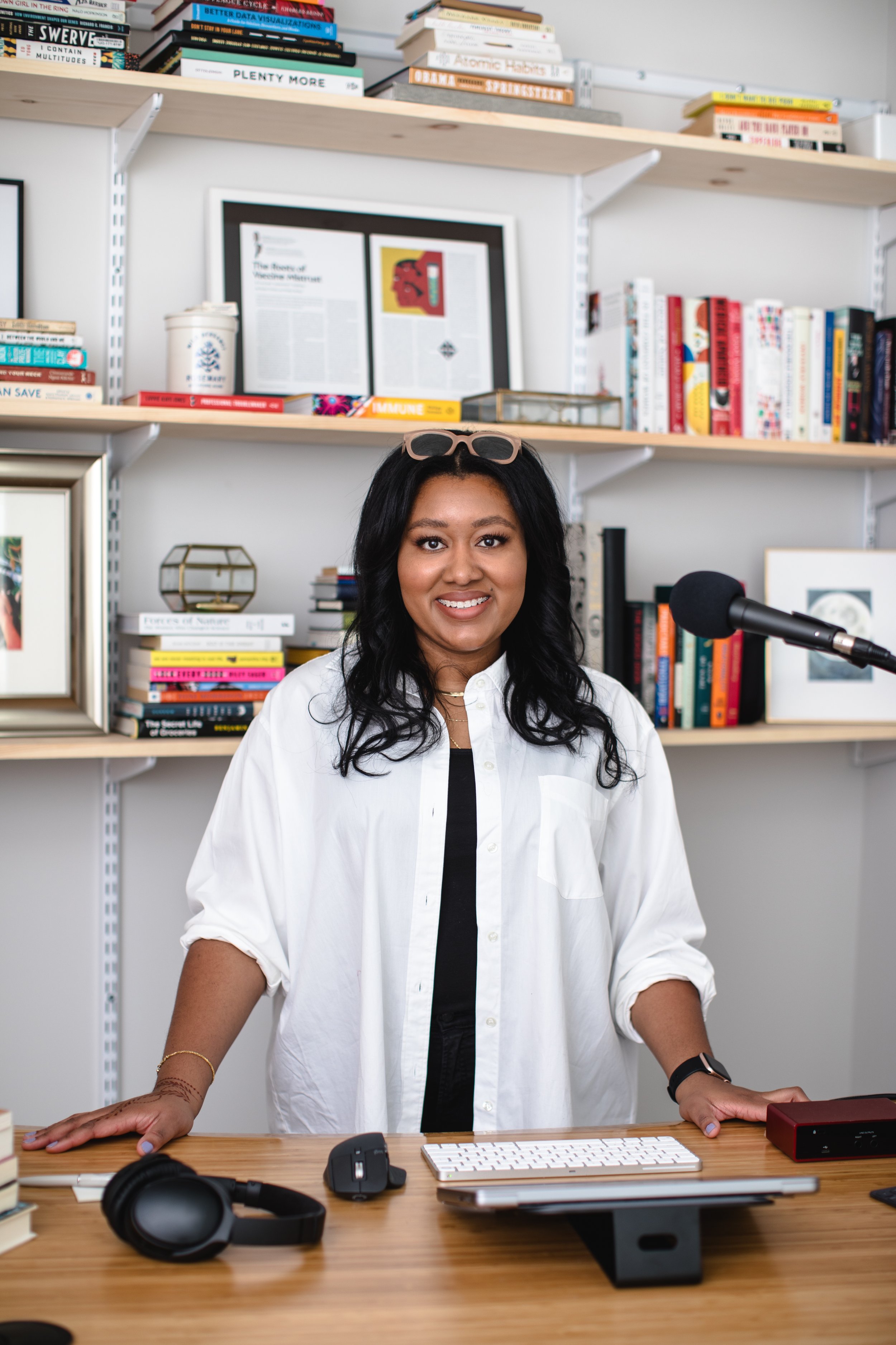Zakiya Whatley standing at desk with podcasting equipment and books behind her on shelves