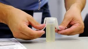 Hands handling a small container or test tube, possibly for medical or laboratory use.