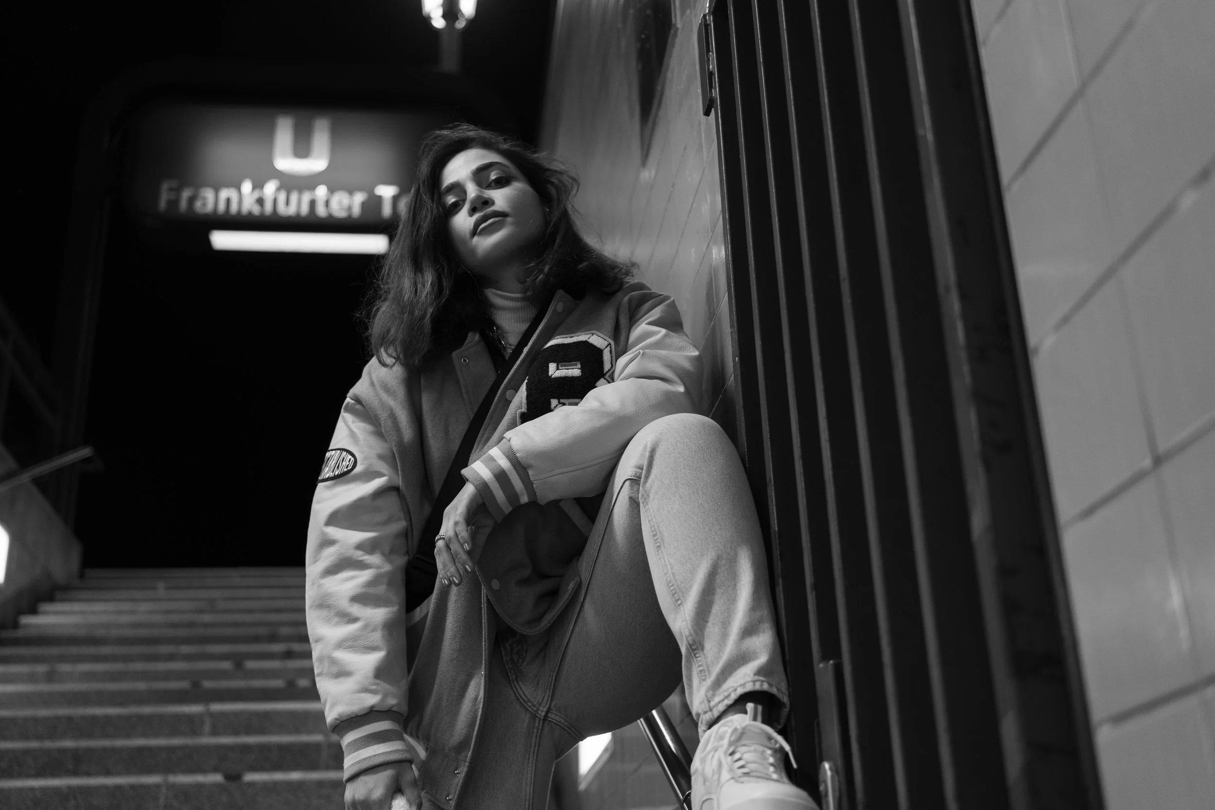Schwarz-weiß-Foto einer Person, die an einer Treppe im U-Bahnhof Frankfurter Tor in Berlin lehnt. Fotograf Christoph Rutenkolk