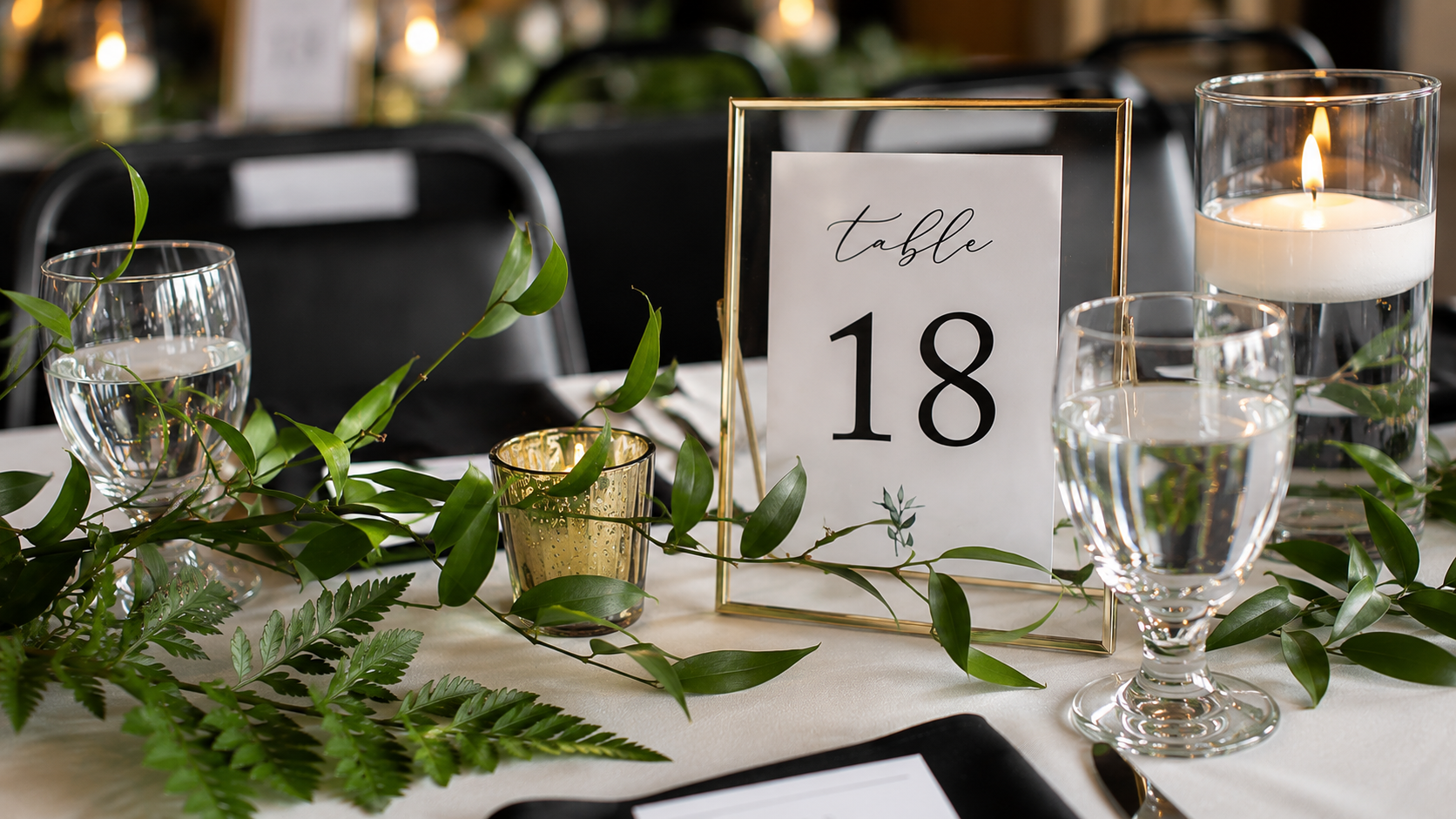 Wedding table scape with gold and floating candles, table number, greenery, and table number