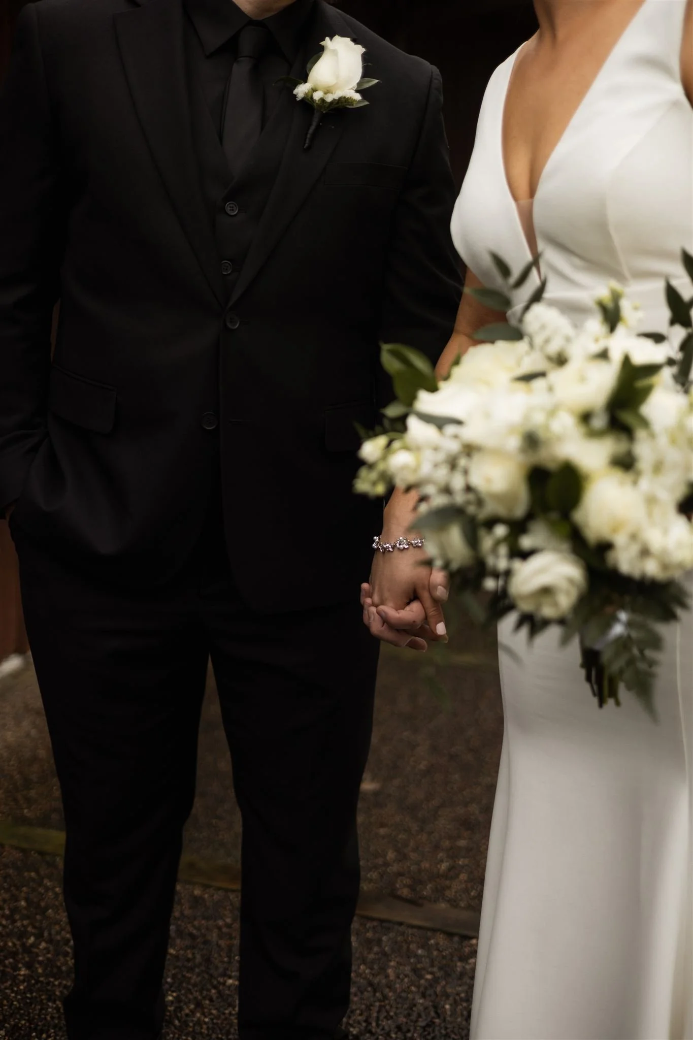Bride and groom holding hands with white and green florals