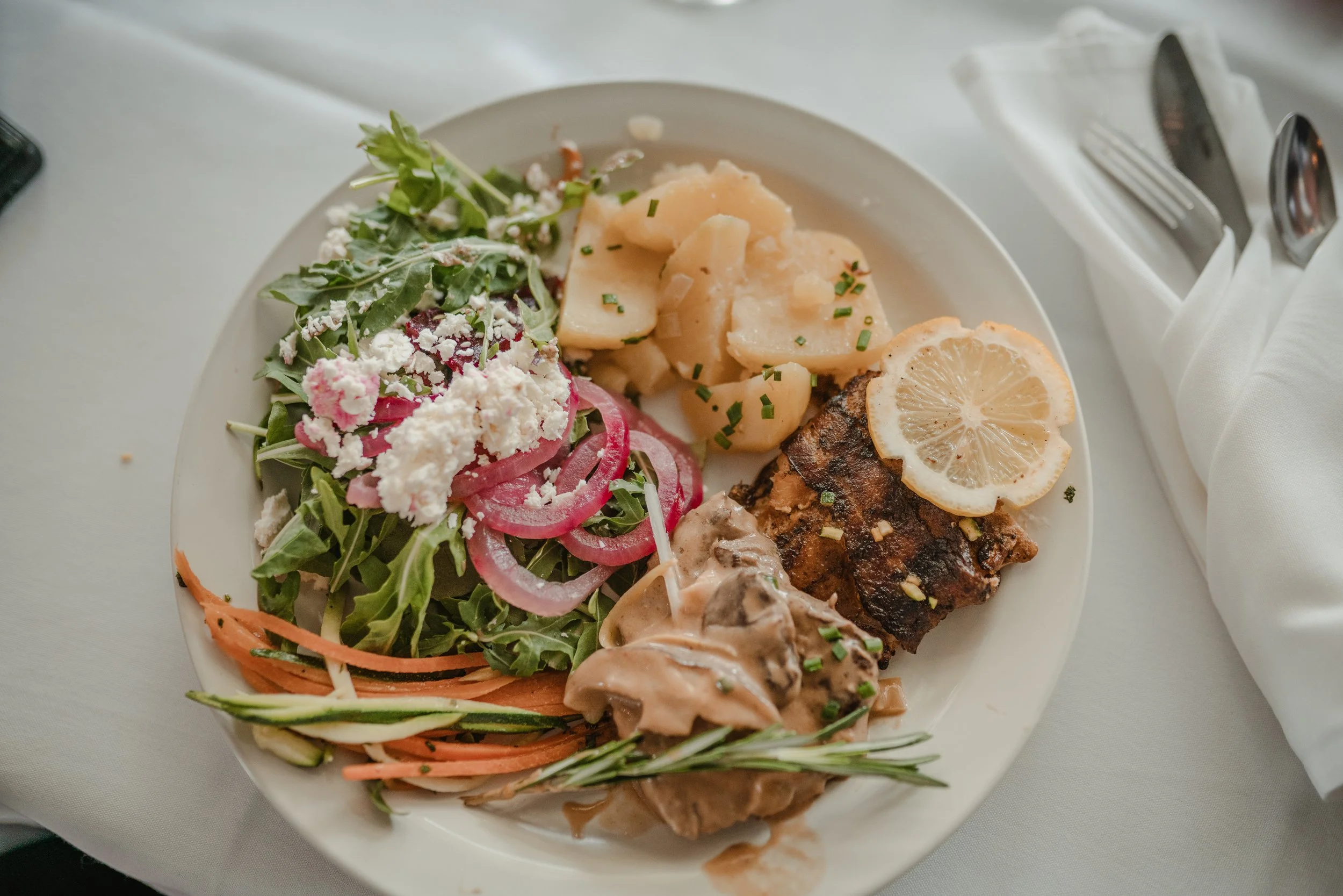 Wedding plate featuring salad, potatoes, vegetables, and chicken with lemon