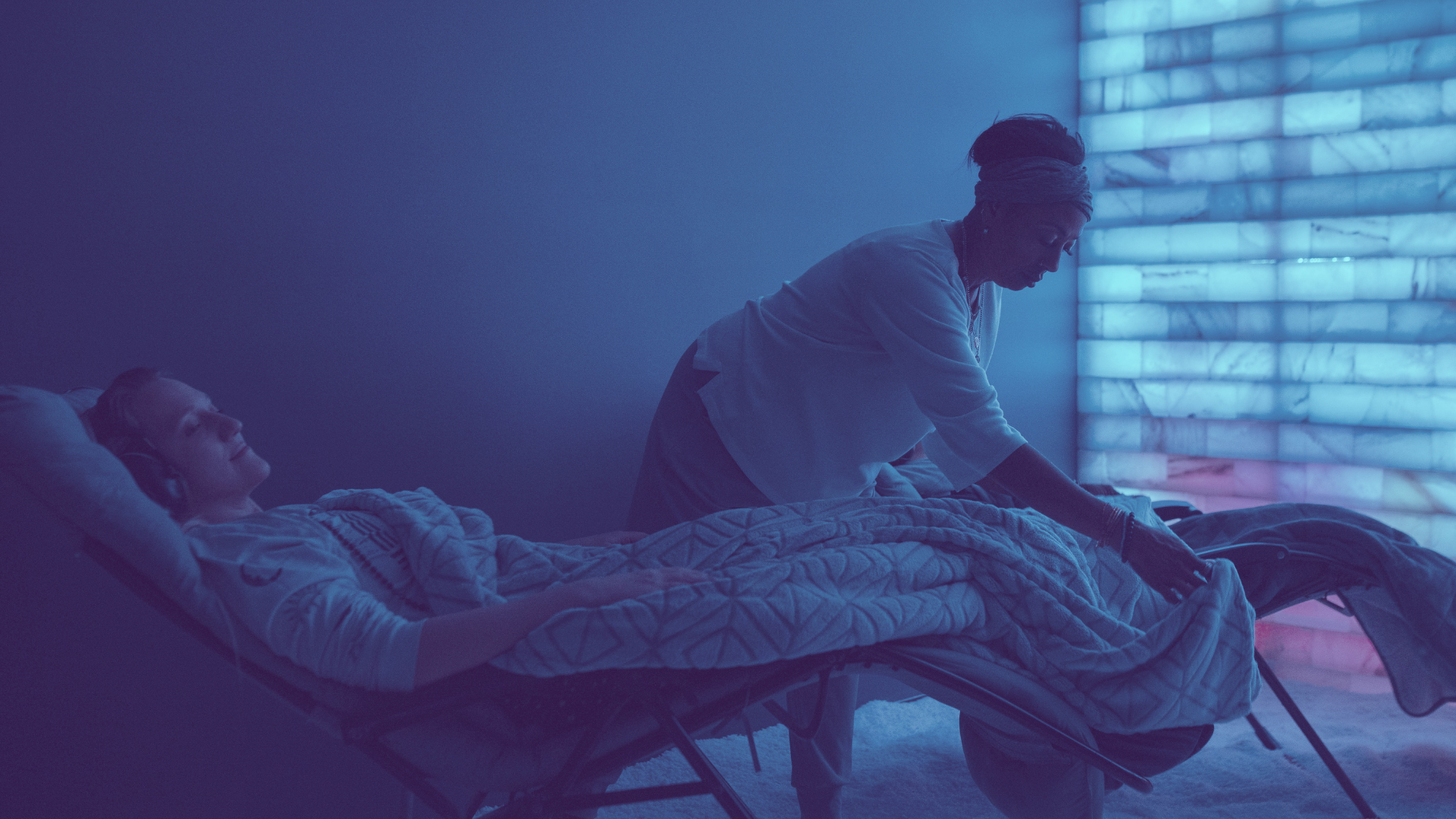 A staff member drapes a blanket over a client resting in the Salt Longe at Inner Space, a clinical wellness center in Des Moines Iowa.