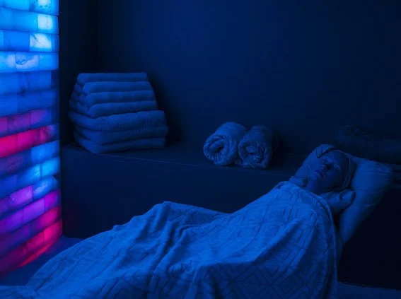 A guest faces the glowing salt wall and experiences deep relaxation in the salt lounge, halotherapy at Inner Space in Des Moines Iowa