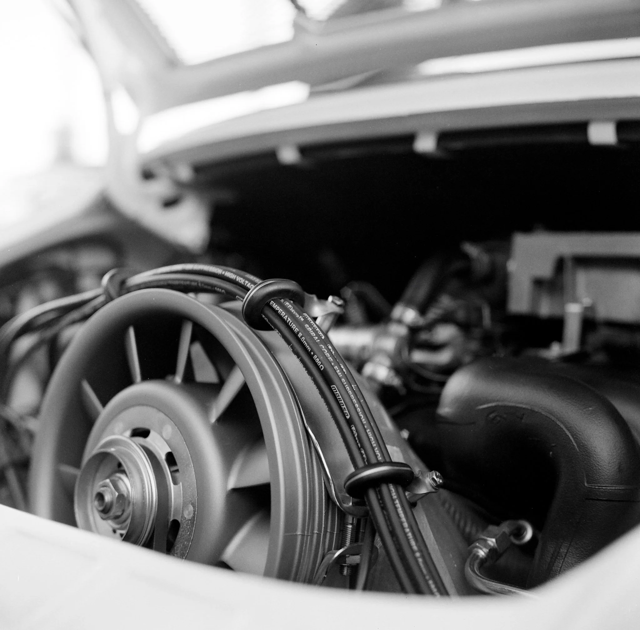 Close-up of a turbine inside a vintage race car engine compartment, black and white photo.