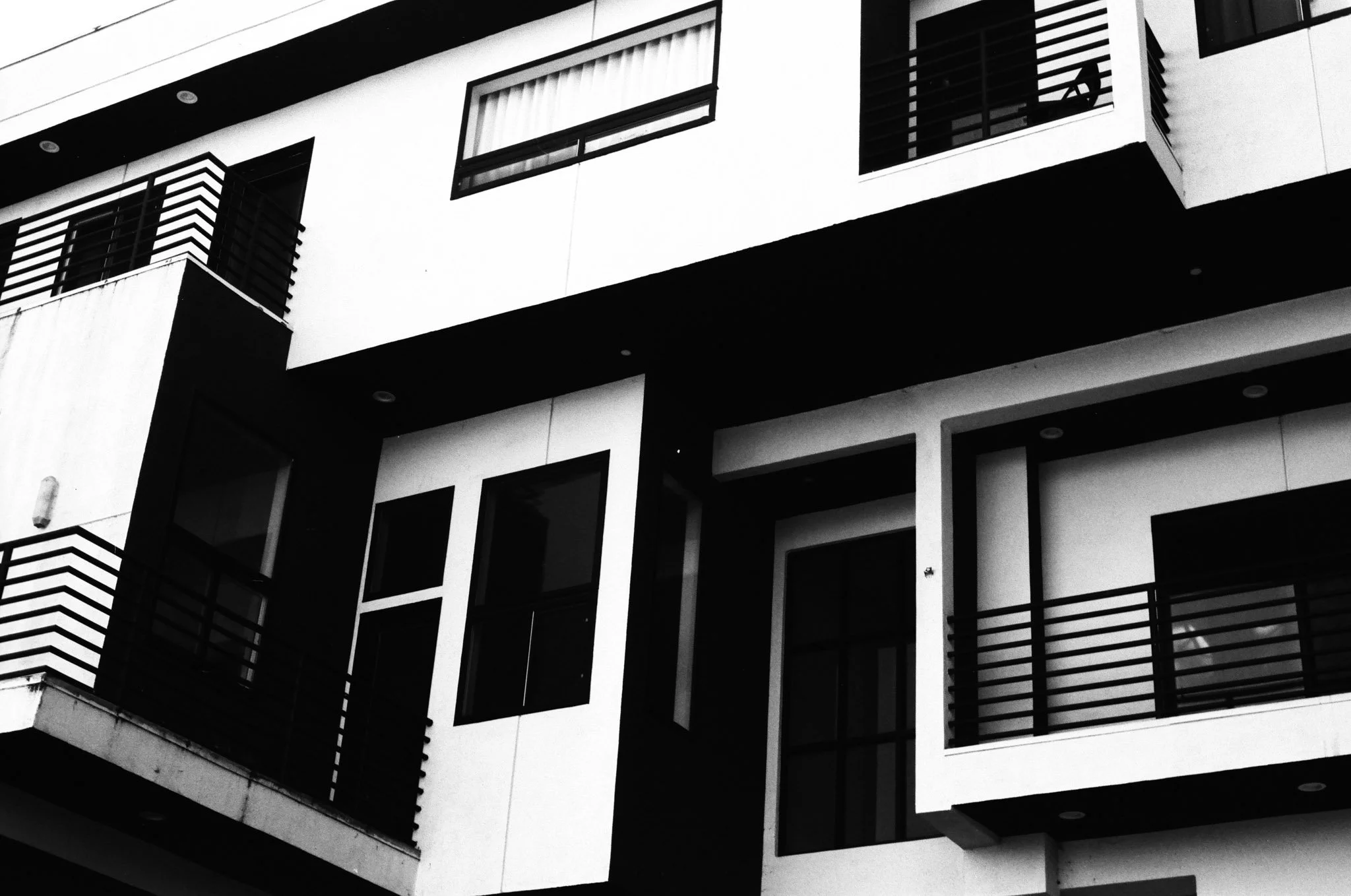 Black and white photo of a modern multi-story apartment building with balconies and large windows.