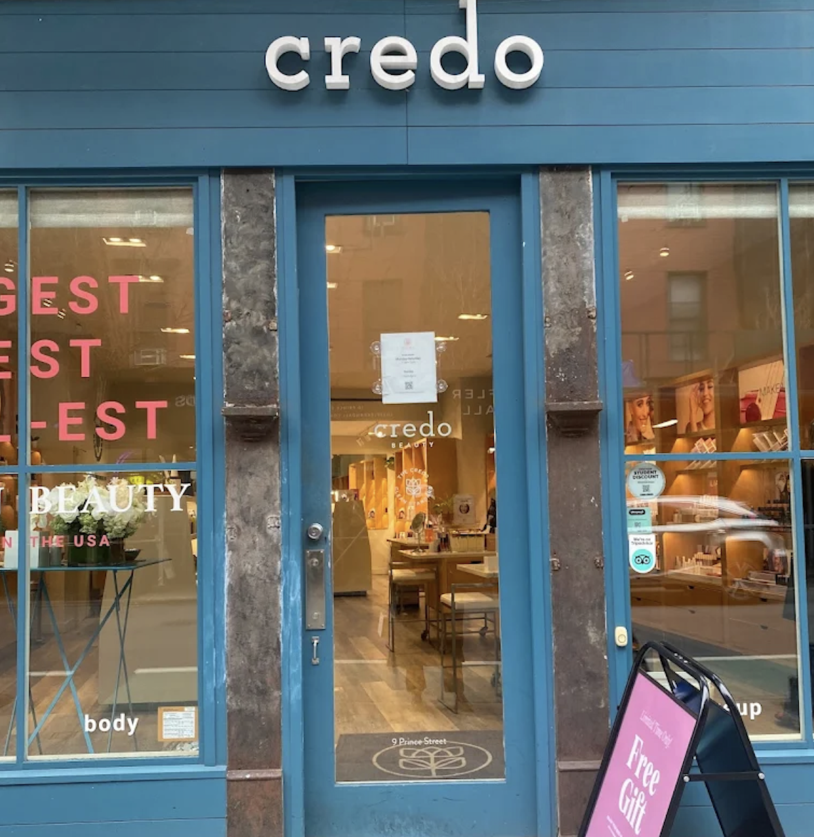 The storefront of Credo beauty with glass doors and windows, displaying the store's interior and signage advertising free gifts.