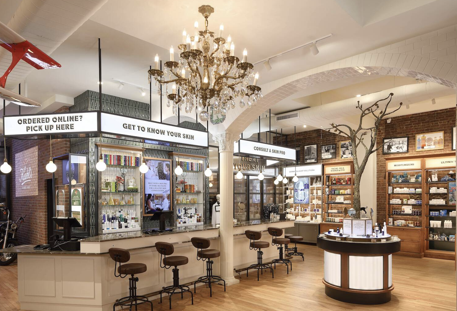 Interior of a skincare or beauty store with display shelves of products, seating, a chandelier, and signage