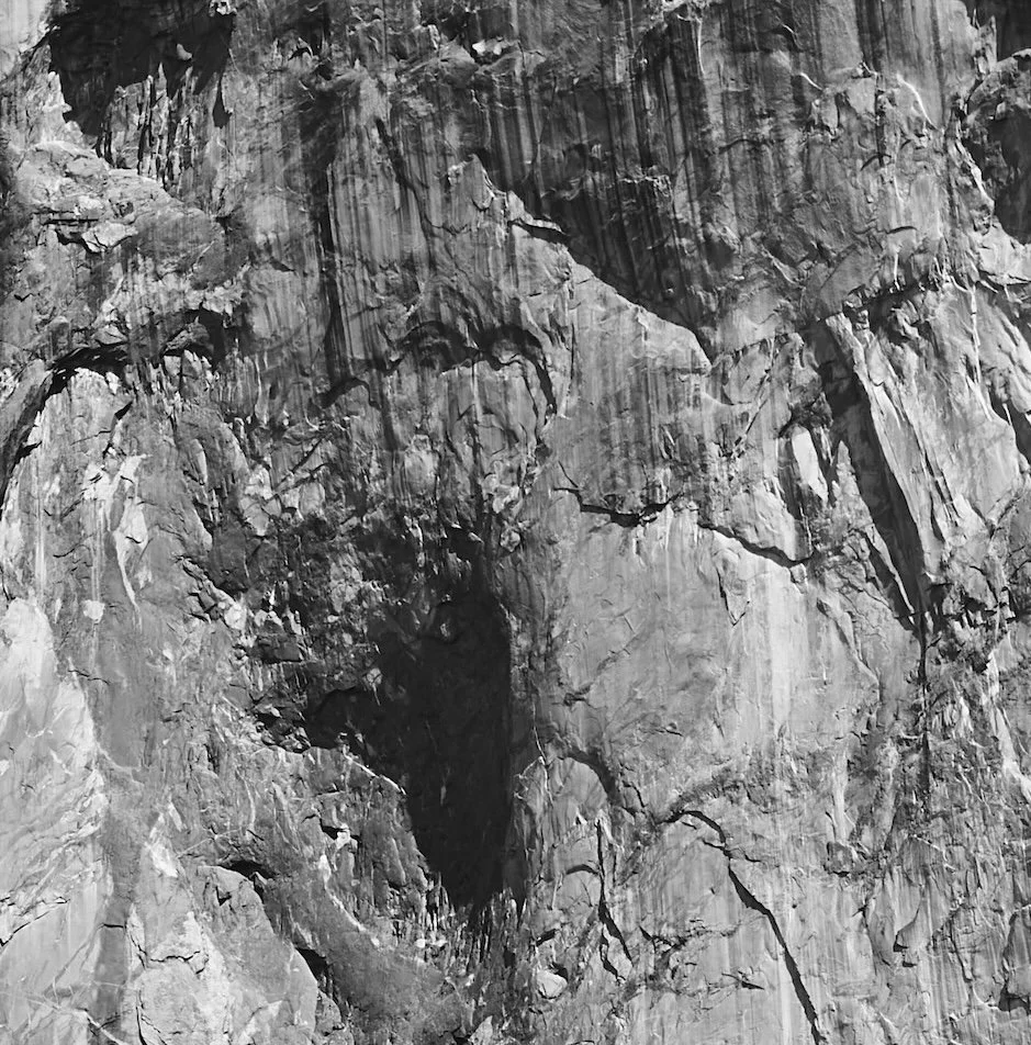 Black and white photo of a mountain rock face with cracks and crevices.