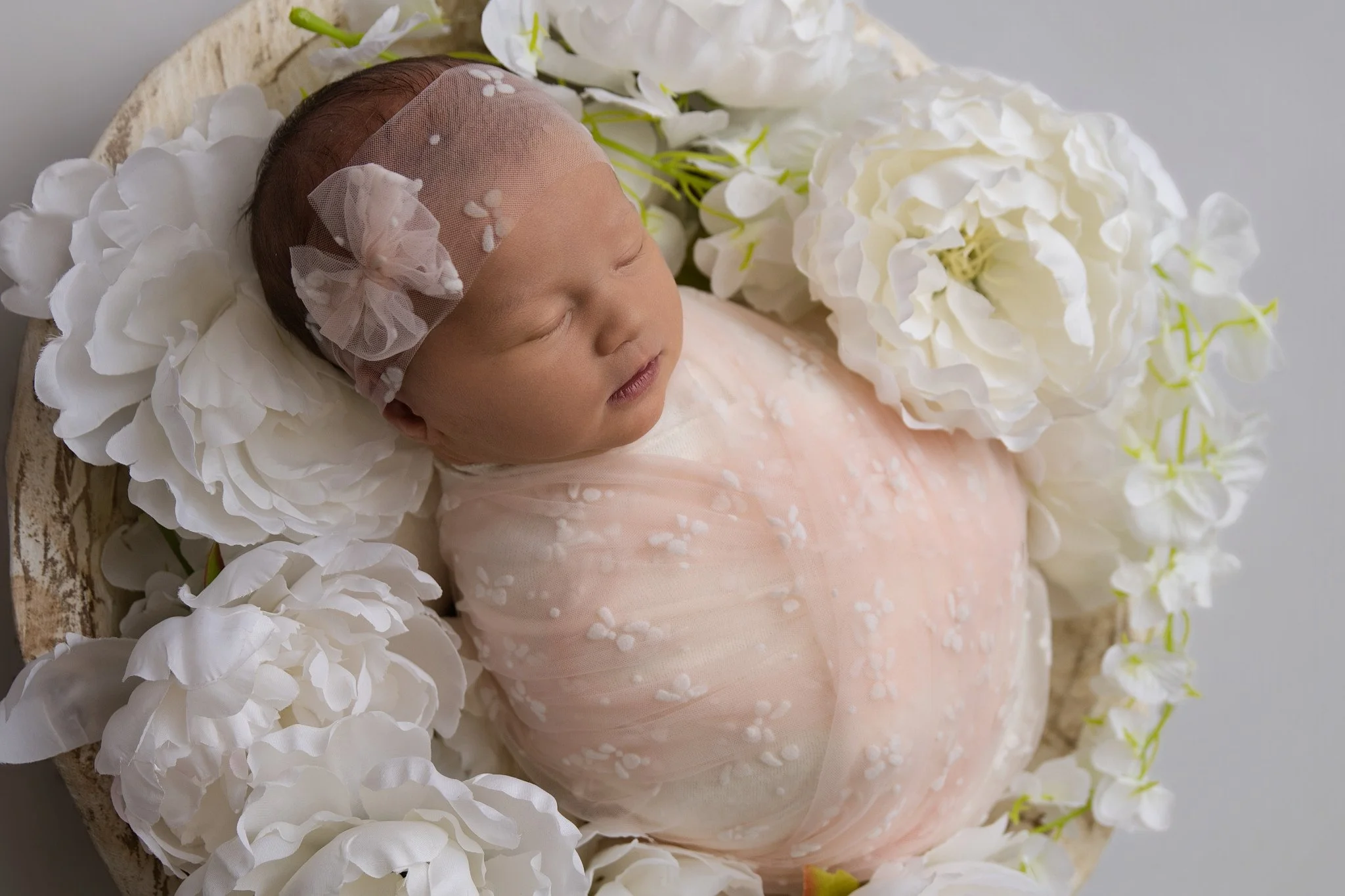 A newborn baby sleeping on a blue textured blanket, with a blue blanket above that has the name 'elliott' written in colorful, glittery letters and a heart symbol.