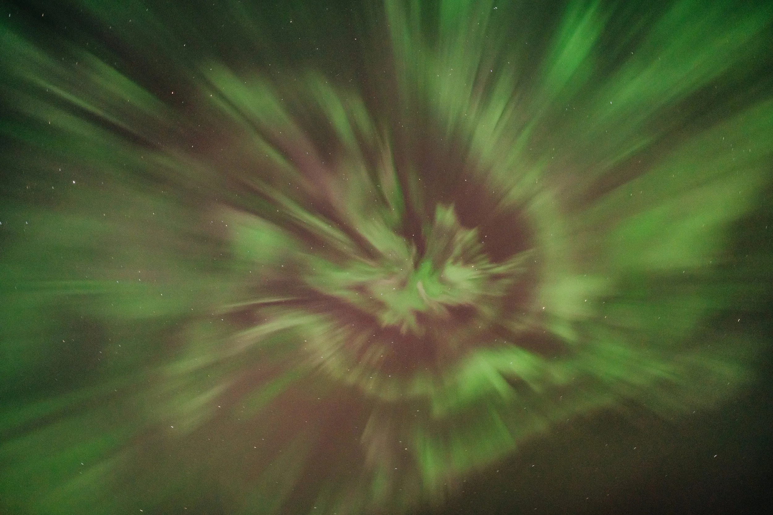 Green and purple aurora borealis in the night sky with stars visible.