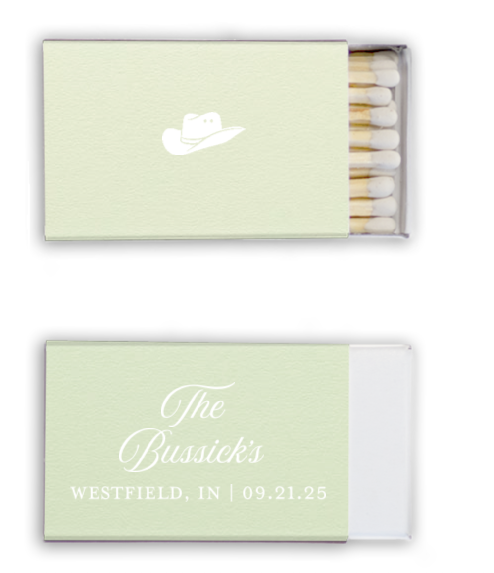 A matchbox with light green cover and white wrap, featuring a cowboy hat logo and personalized wedding details including names, location, and date.