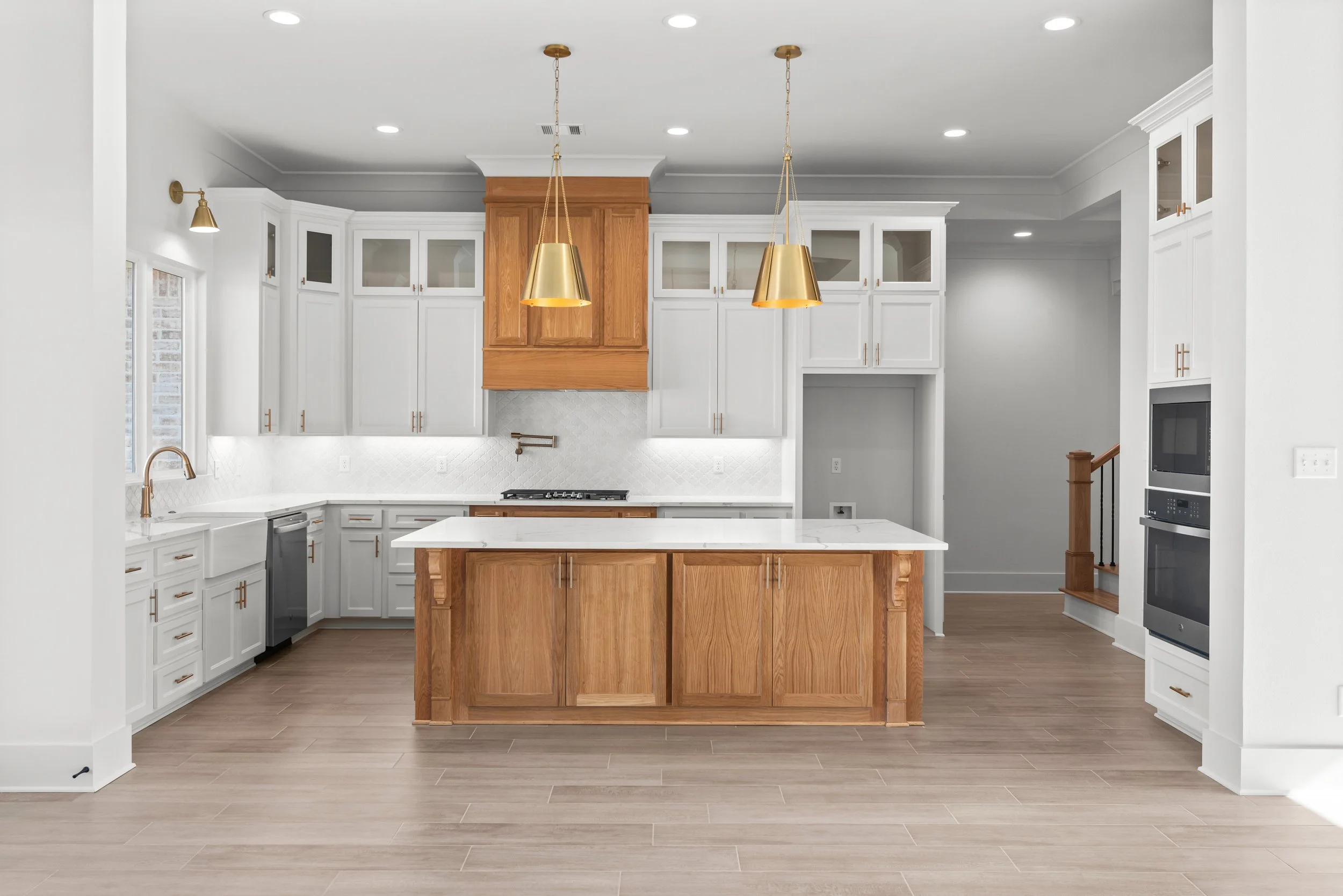 Modern kitchen with white cabinets, a wooden island, pendant lights, and a built-in oven.