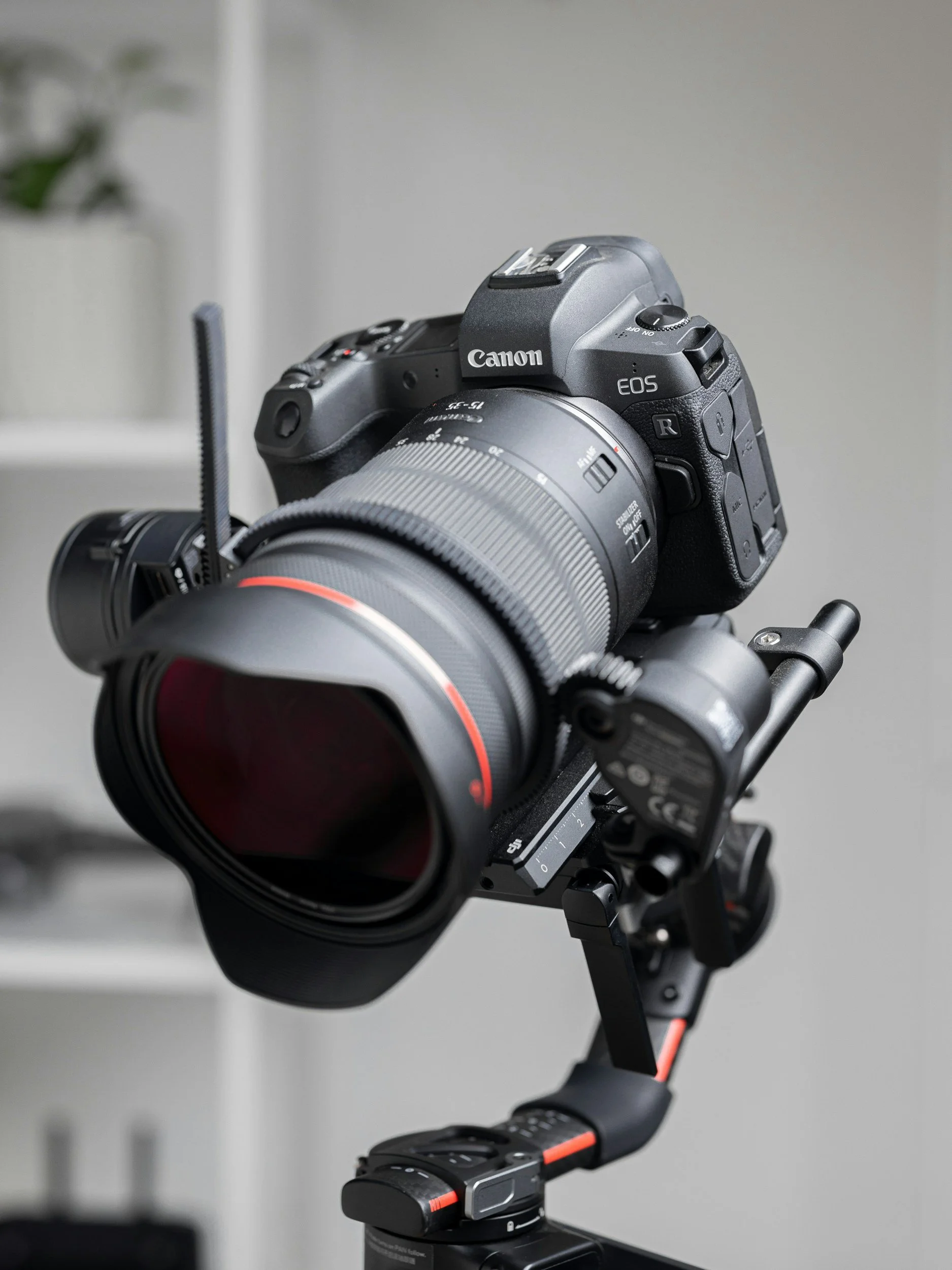 A professional Canon EOS camera with a large lens mounted on a stabilizer rig, set indoors.