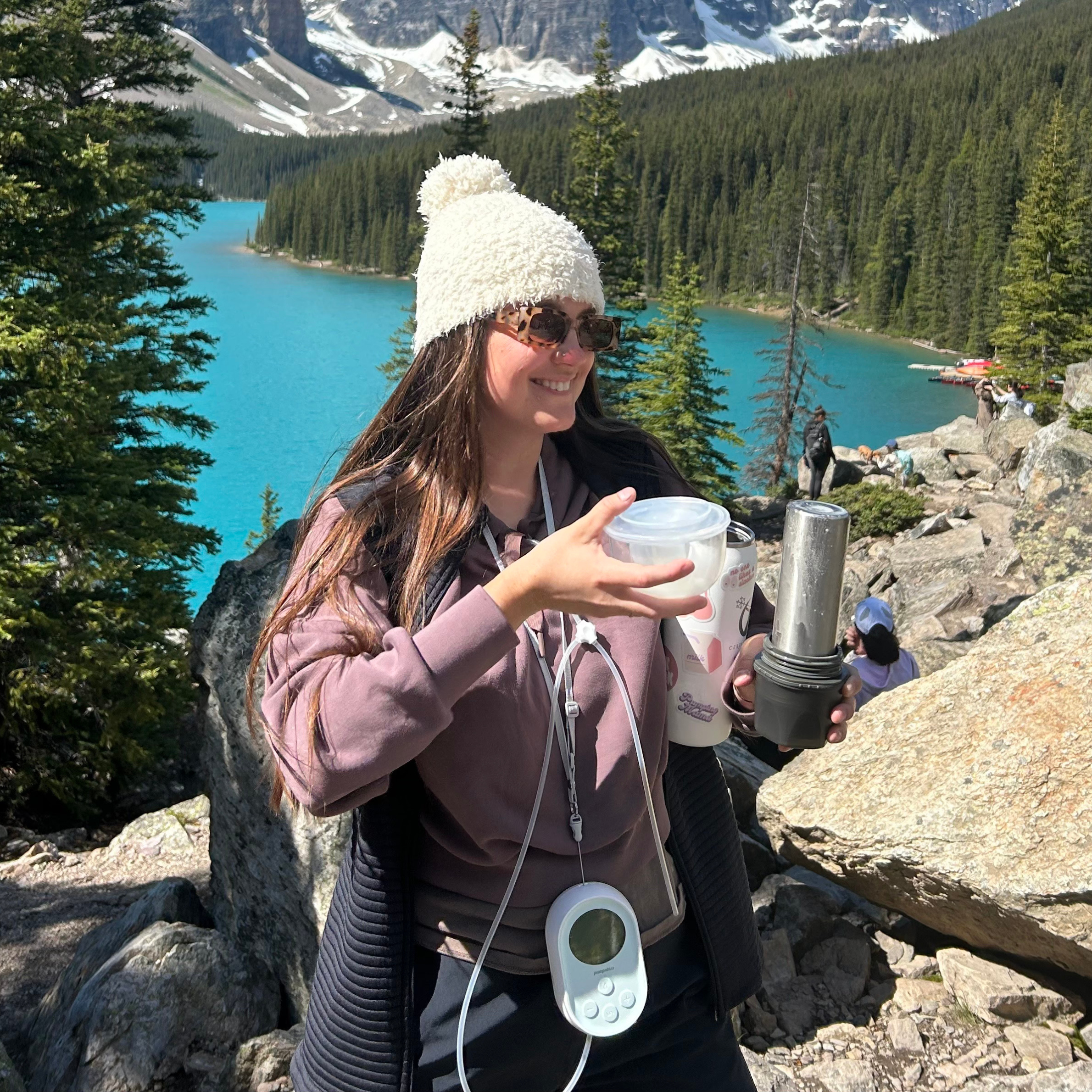 Mom hiking in the mountains while wearing a portable breast pump and pouring pumped milk into a Ceres Chill chiller