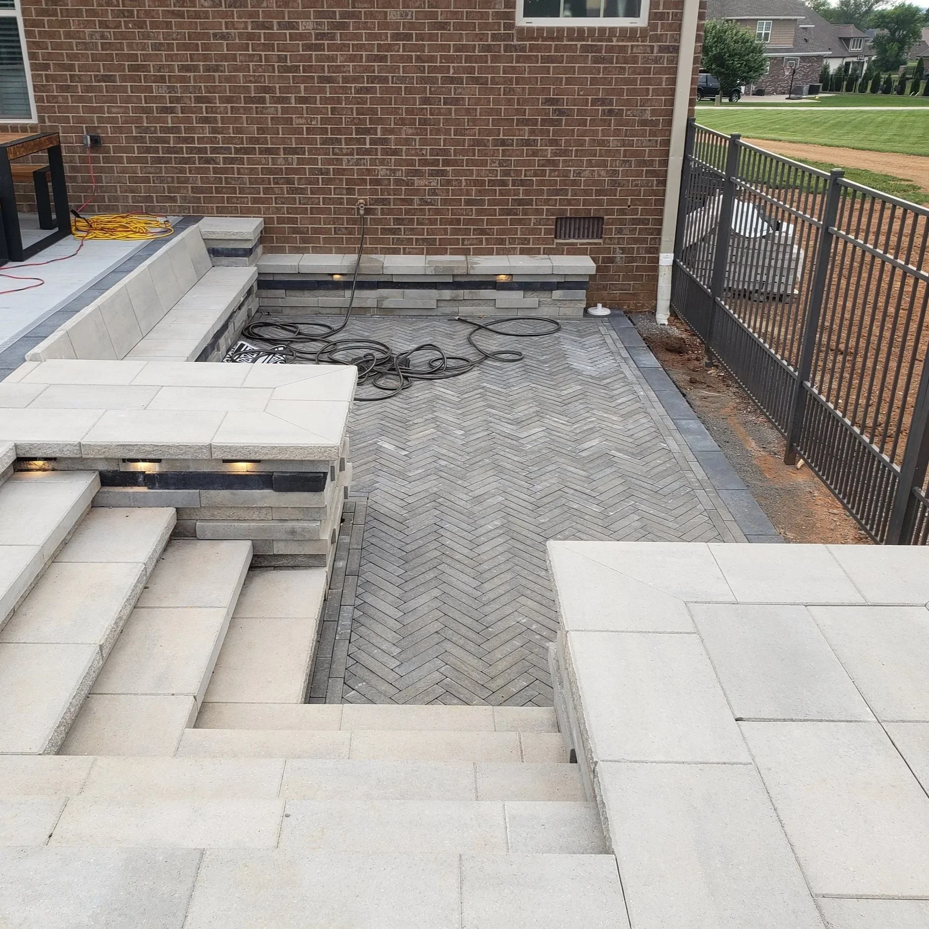 Custom paver patio with herringbone pattern, concrete steps, and retaining wall lighting in Sumner County Tennessee