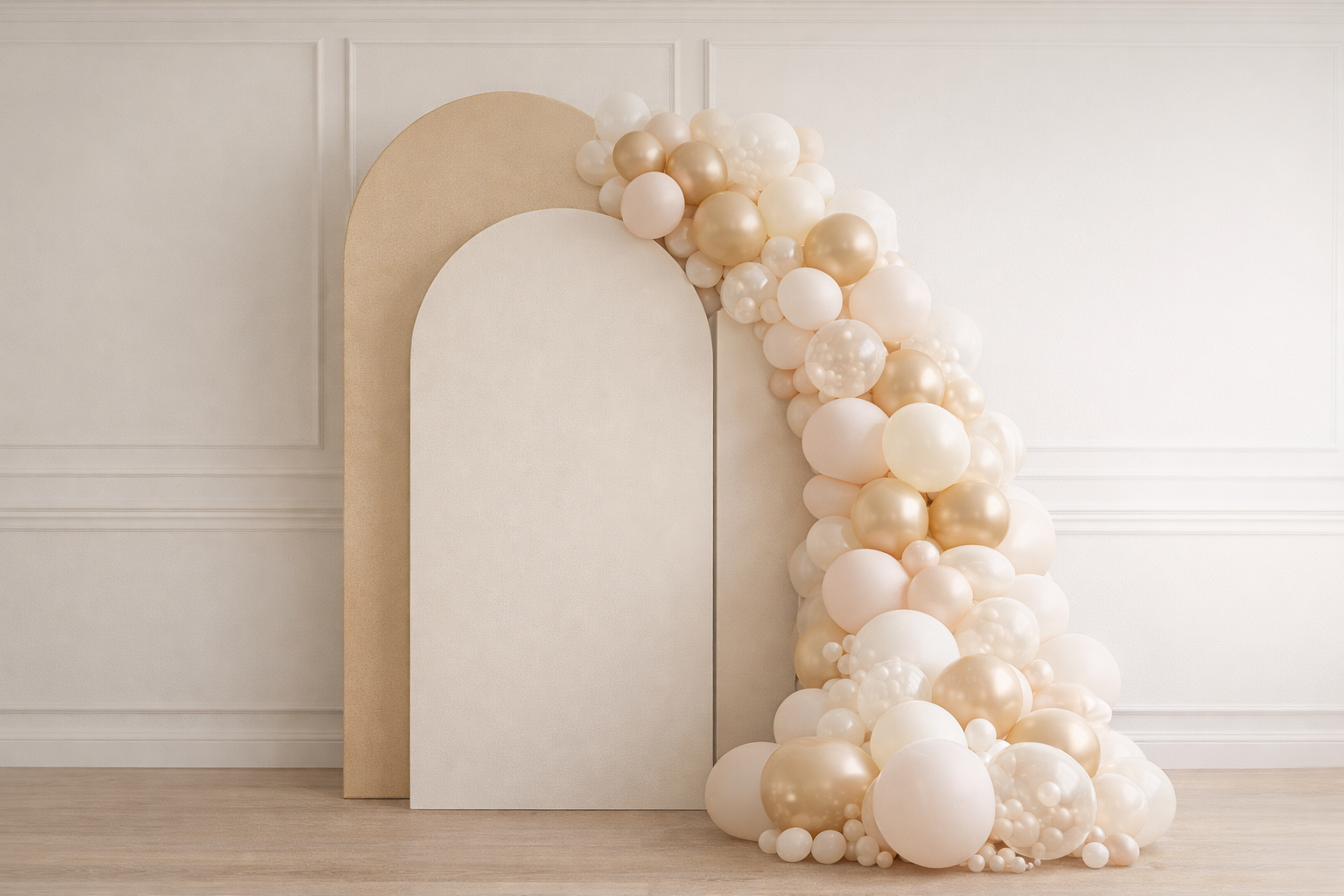 Decorative backdrop with white, cream, and gold balloons arranged along a beige and white panel in a minimalist room.