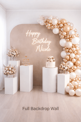 A birthday celebration setup with a beige backdrop featuring 'Happy Birthday Nicole' written on it, decorated with clusters of white and gold balloons on the right. There are four white pedestals with floral arrangements and a cake on the center pedestal, all set against a white wall.