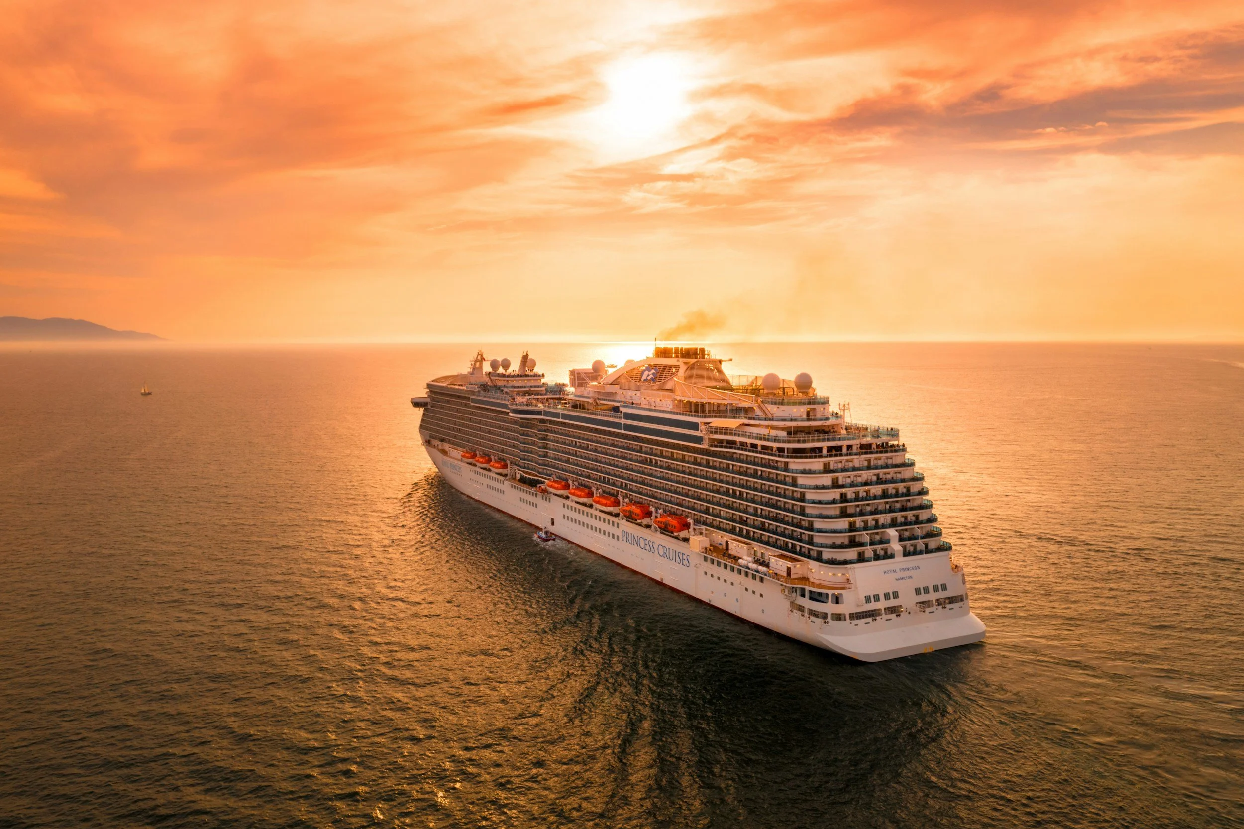 A cruise ship sailing the ocean at golden hour.