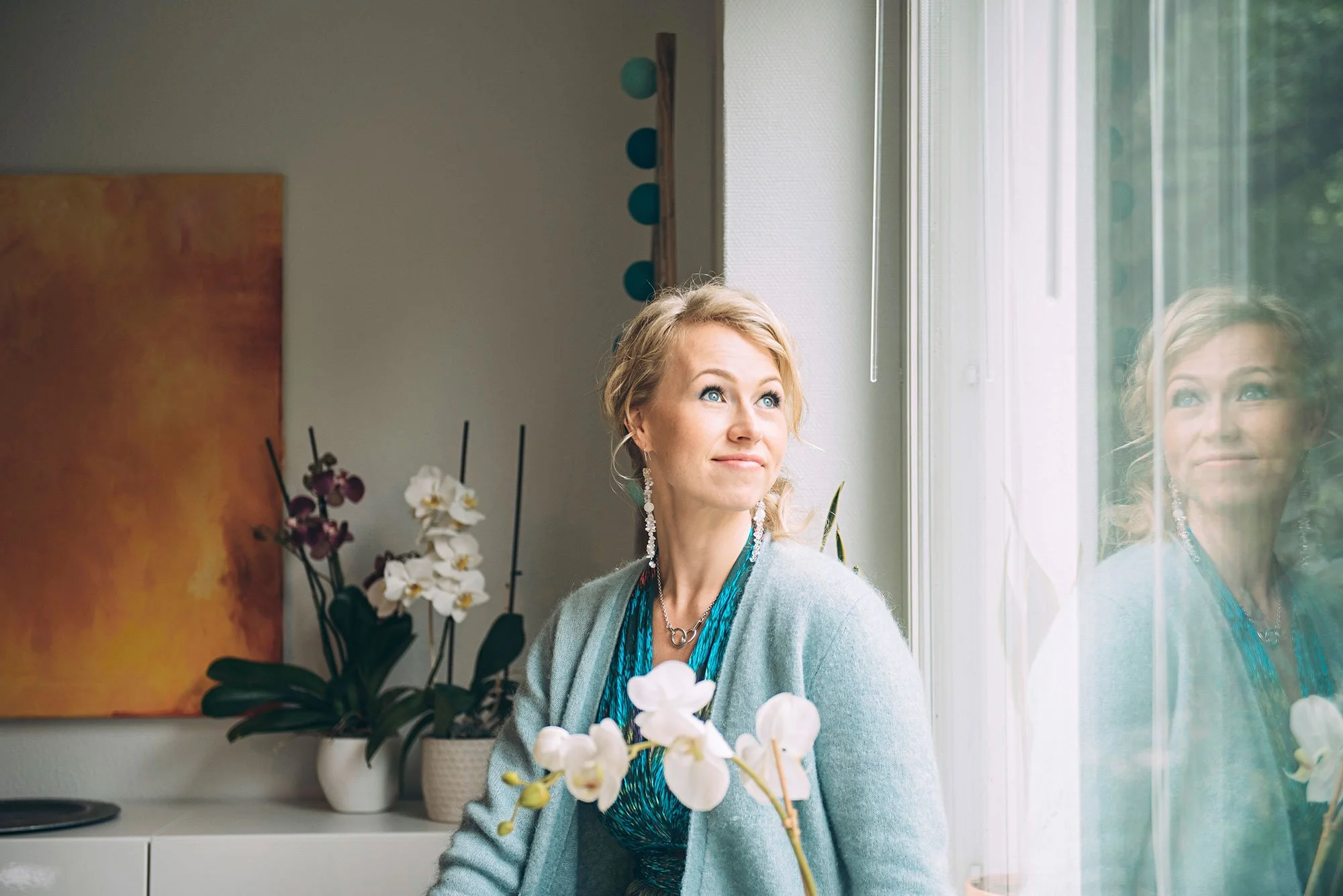 Kaisa Jaakkola katsoo ikkunasta, ikkunan kautta näkyy heijastus hänestä.
