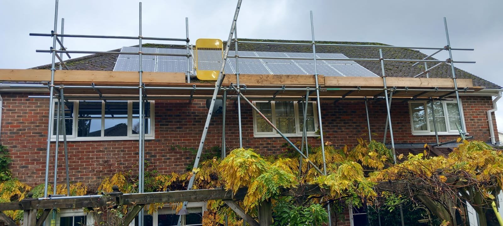 Scaffolding providing safe roof access around existing solar panels for roofing or property maintenance work. West Sussex Coastal Scaffolding Ltd.