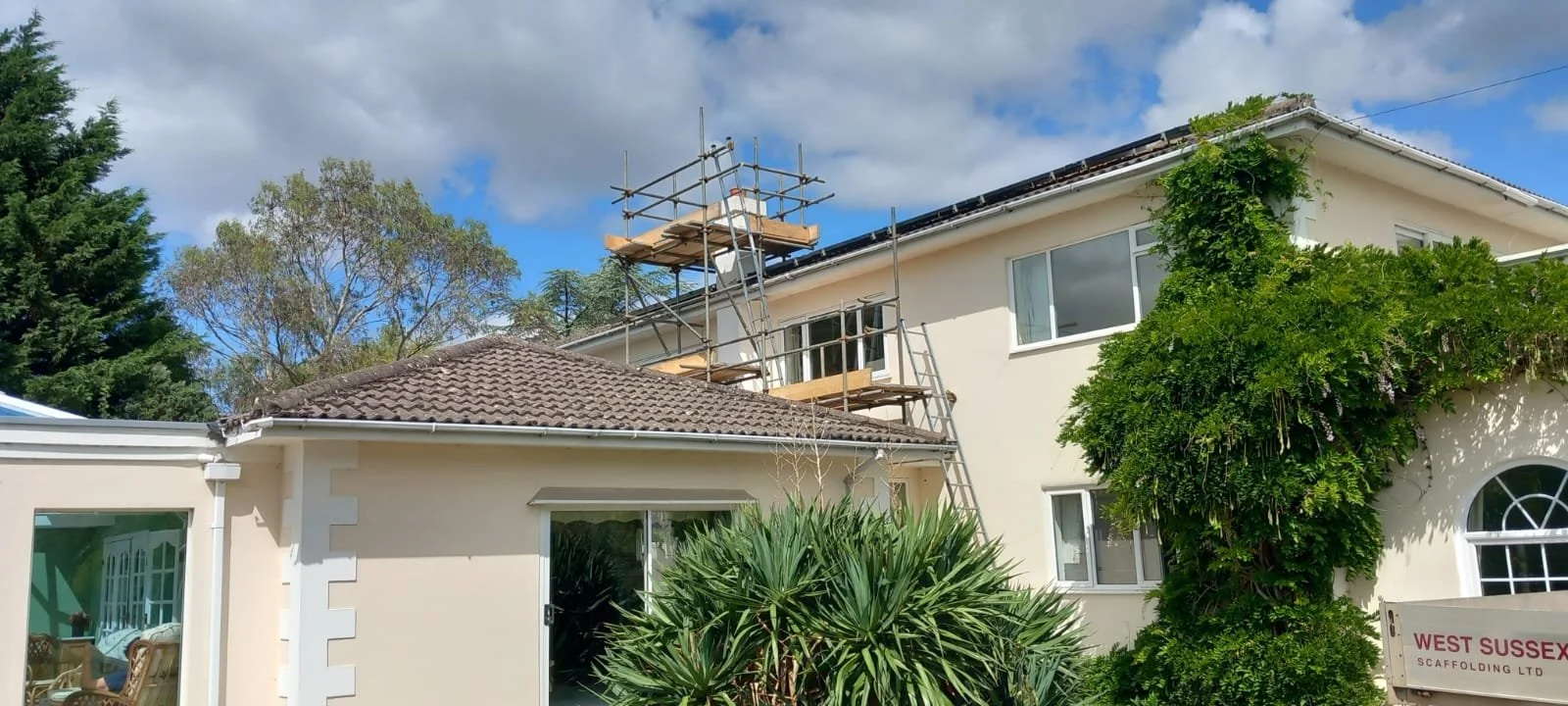 Domestic scaffolding erected around a house for roof works, providing safe access to the upper roof area. West Sussex Coastal Scaffolding Ltd.