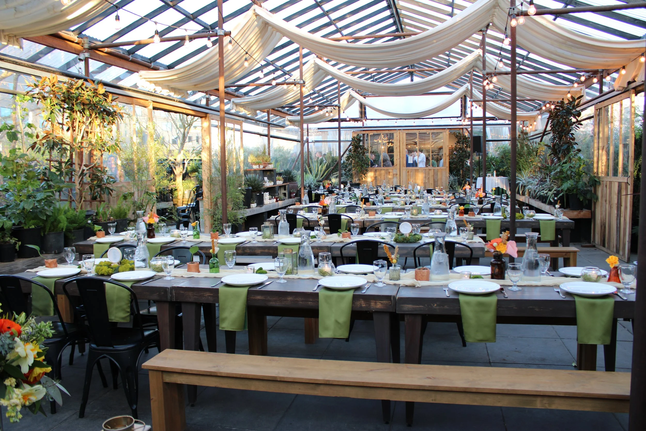 A beautiful greenhouse with farm table decor with fabric floral decor and green napkins