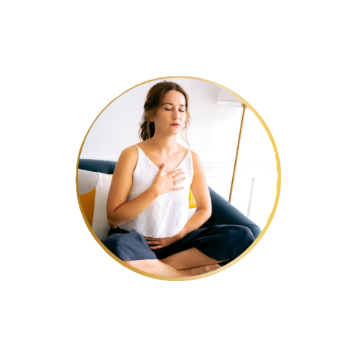 Une femme assise en méditation ou en pleine relaxation, mains sur le cœur, dans une pièce bien éclairée.