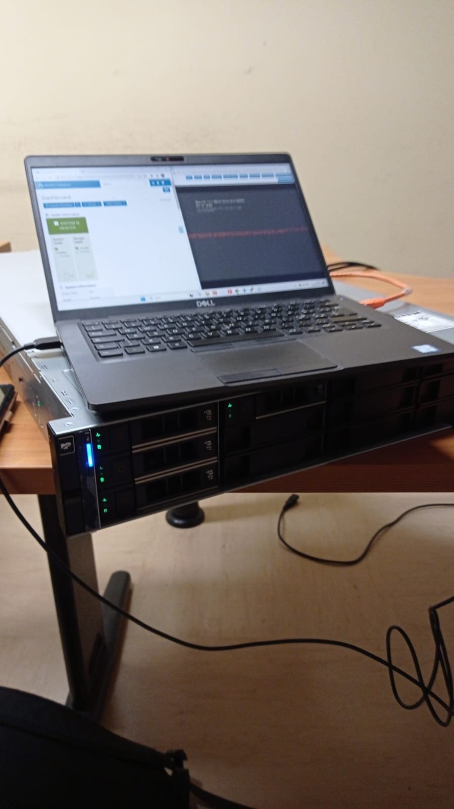 Un laptop aperto su un server rack posizionato su un tavolo. Il laptop mostra una schermata con codice e dashboard per la gestione di un server. Cavi collegati al dispositivo.