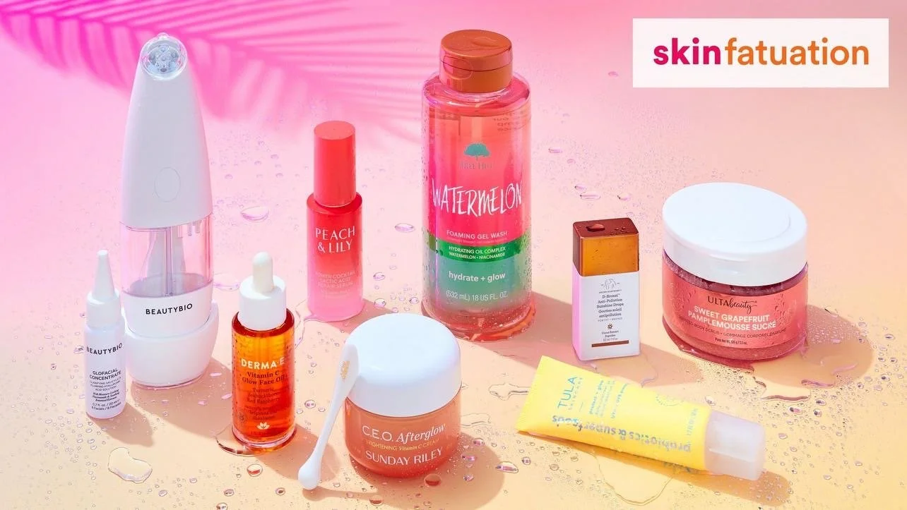An assortment of skincare products, including a facial steamer, moisturizer, serum, cleanser, and creams, arranged on a pink and peach background with water droplets, and a 