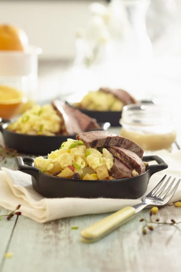 Green beans casserole with sliced beef steak in black baking dish on a light wooden table