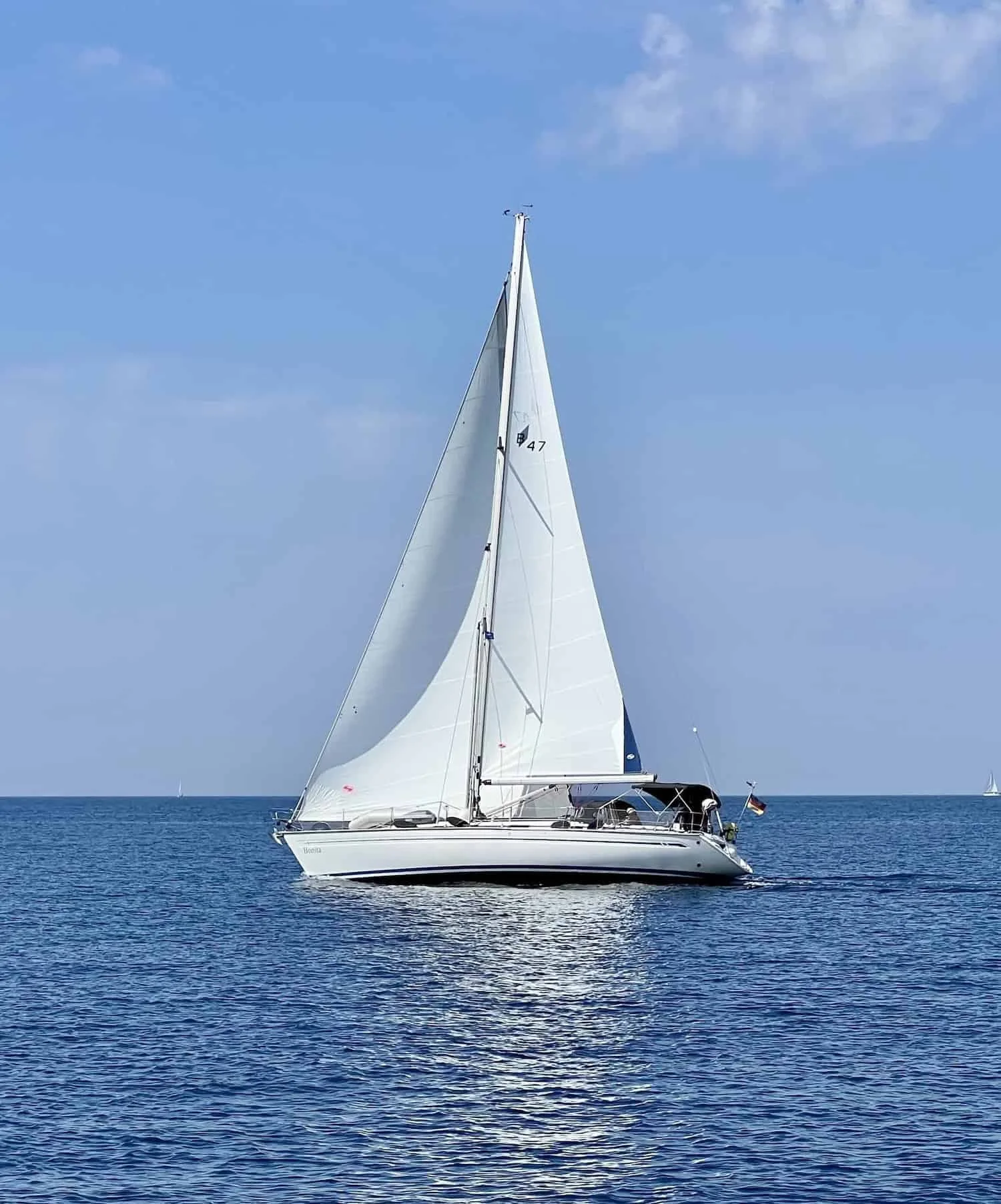 Segelboot auf ruhigem Meer unter blauem Himmel.