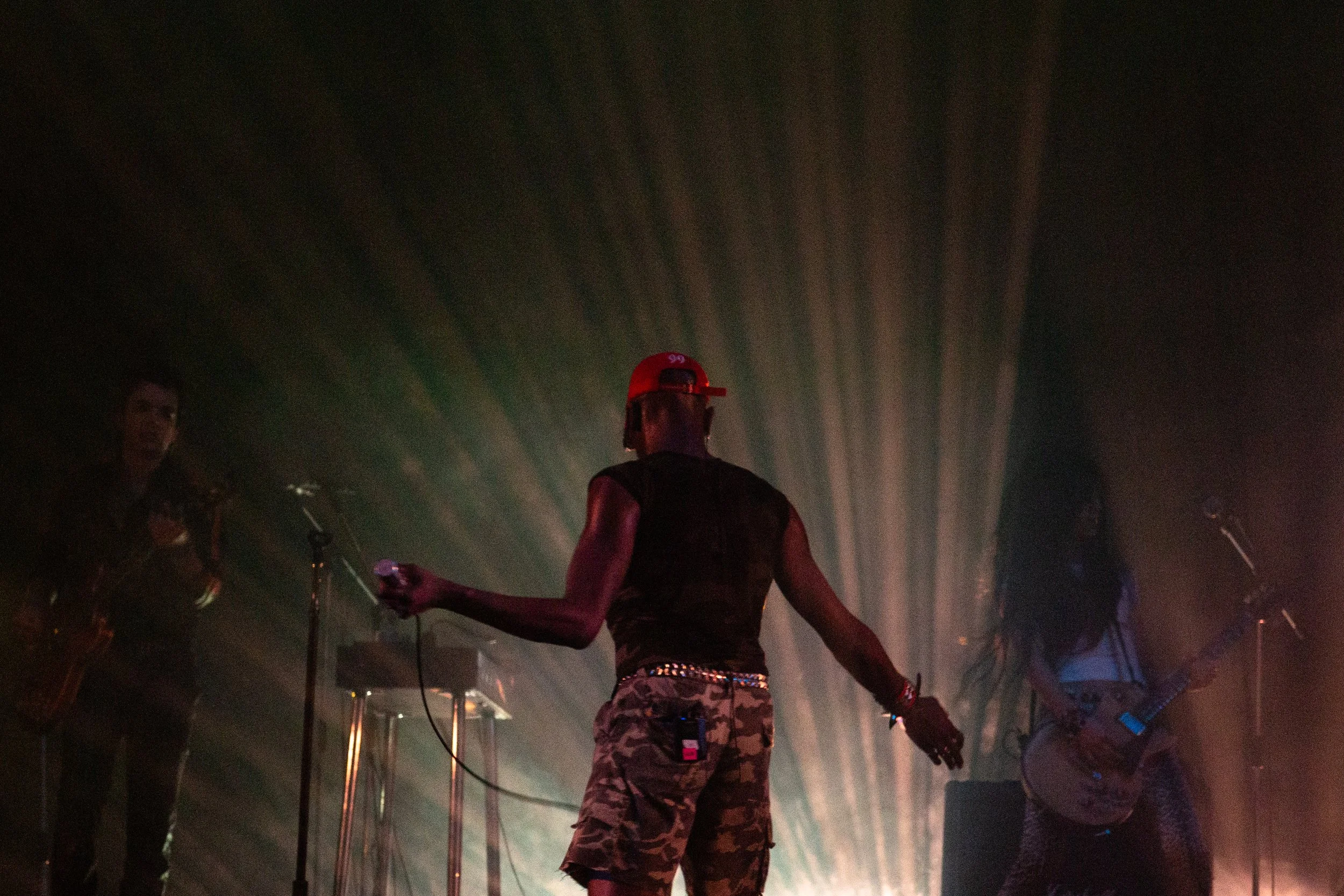 Musicians on stage performing with dramatic backlighting creating a silhouette effect.
