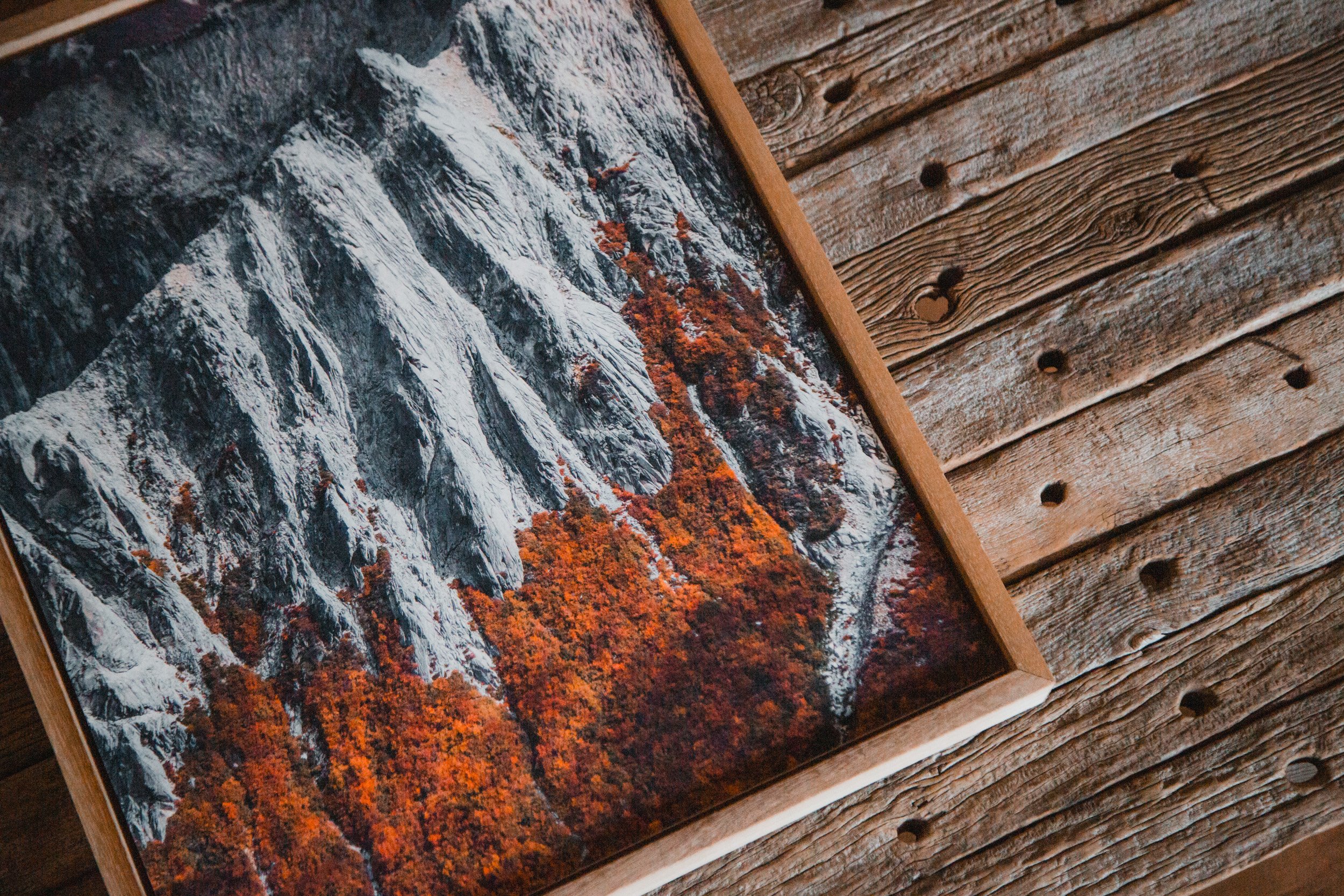 Framed photo of a mountain with autumn foliage on a wooden table