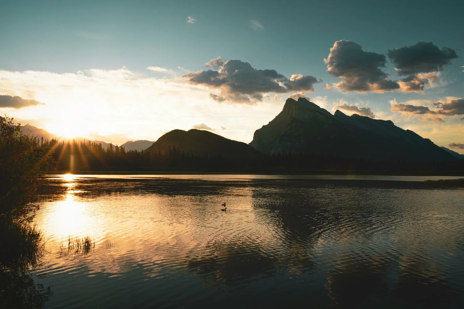 Warm sunlight across a lake beneath a mountain silhouette